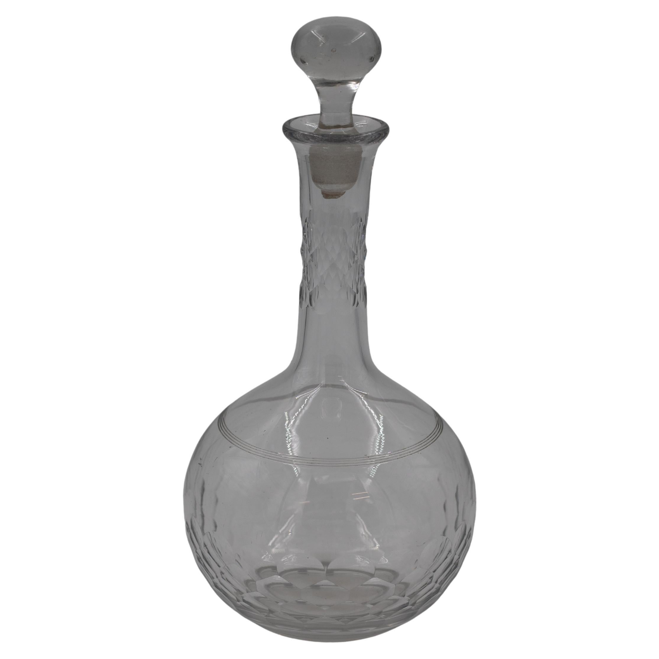 Elegante carafe soufflée à la main, dont le corps arrondi et bulbeux est décoré de facettes taillées à la main qui captent et réfractent magnifiquement la lumière. L'encolure élancée est agrémentée de détails en coupe transversale, ajoutant