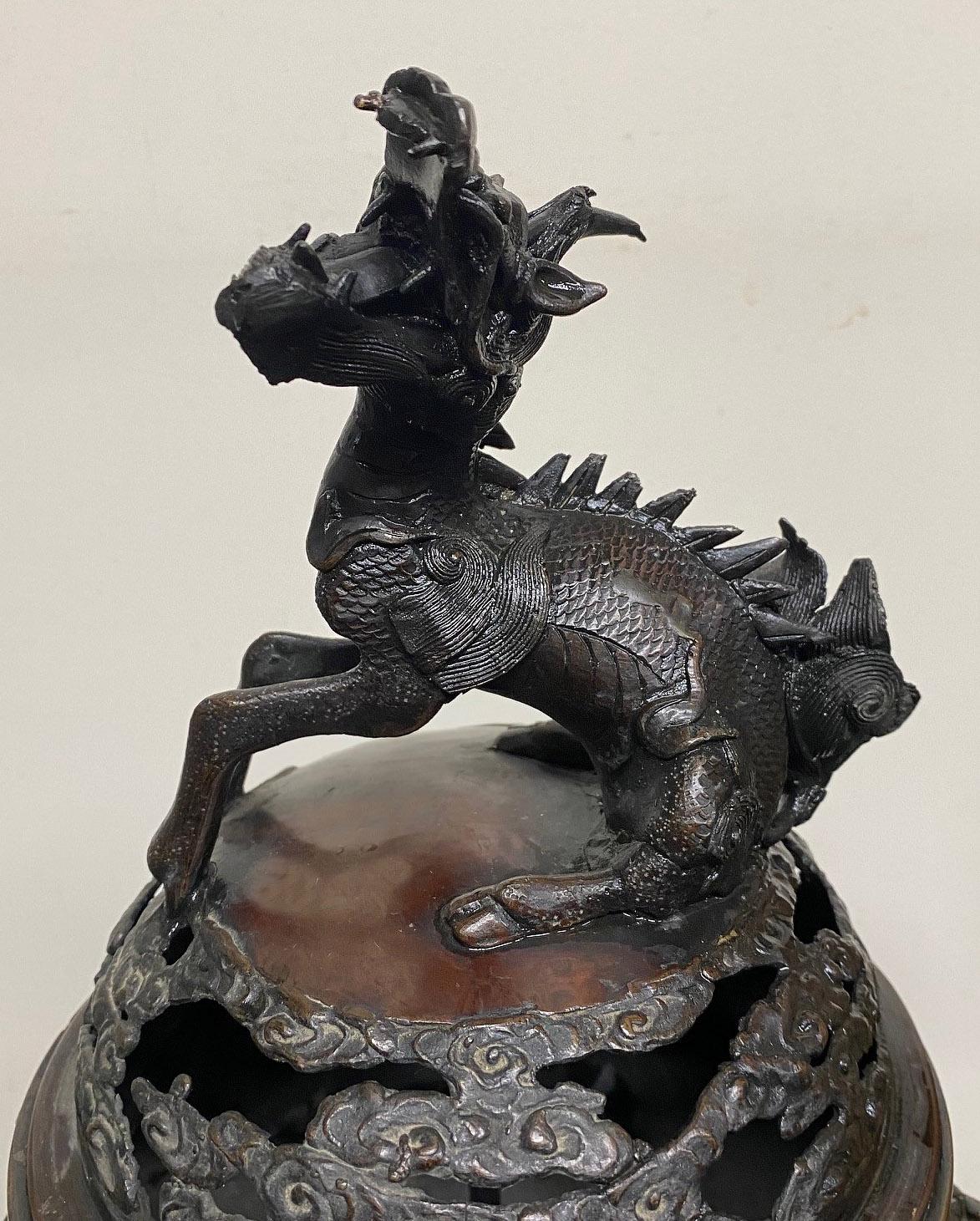 Late 19th/early 20th century Japanese bronze incense burner or cachepot

The cover decorated with a large dragon, the base designed with flowers and birds. There are handles to each side, standing on three legs.