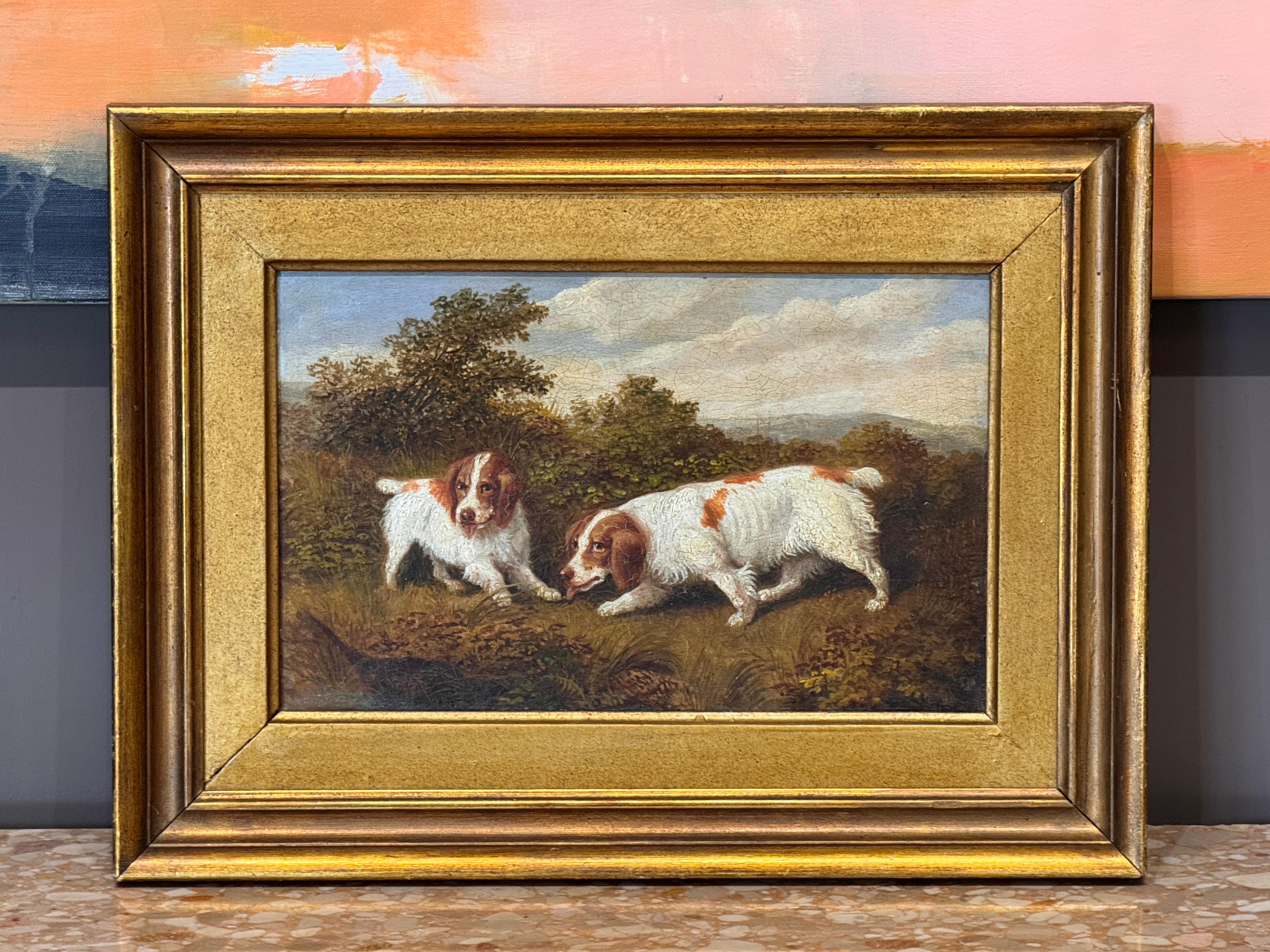 Encantador cuadro al óleo sobre tabla que representa a dos perros de aguas en un paisaje boscoso, representado con gran detalle y calidez. La composición capta un animado escenario natural y se presenta en un marco dorado posterior.
