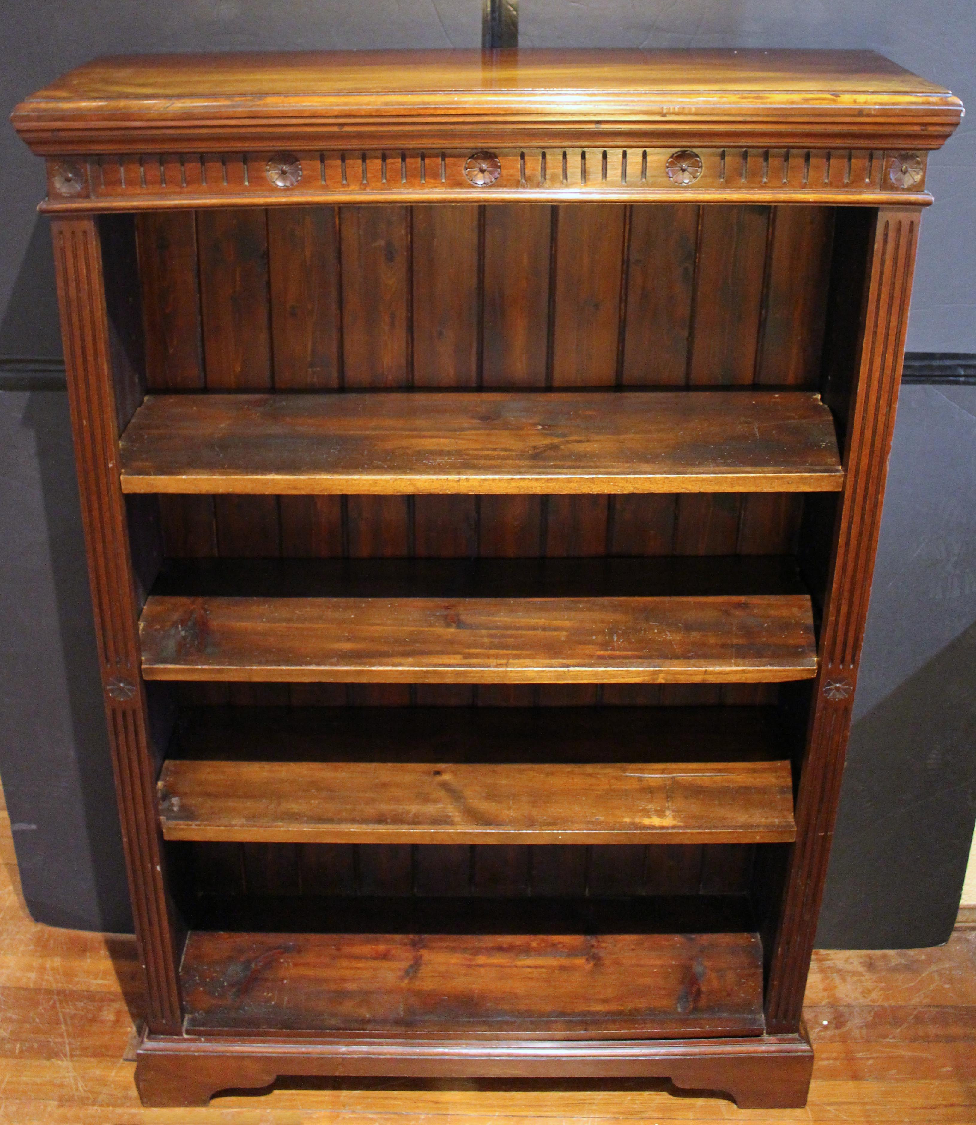 Late 19th-early 20th century open bookcase, English. Three peg supported adjustable shelves. Plinth base with cut out front & solid sides. Well molded crown over frieze of flutes & rosettes, repeated in the uprights. Roughness to the finish on the