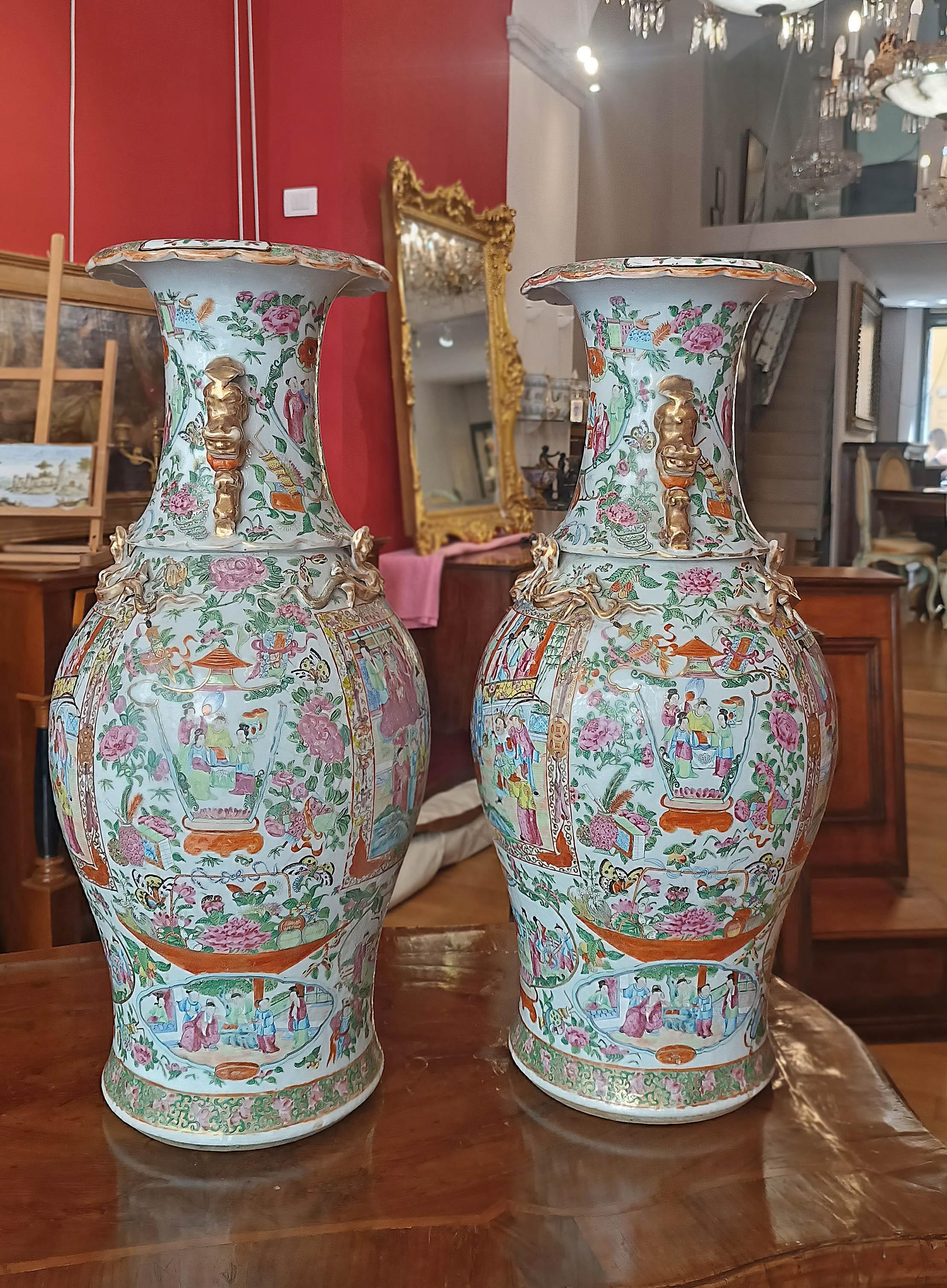 Elegant pair of large polychrome porcelain vases, adorned with decorations and golden finishes. The vases depict scenes of everyday life on the four sides of the neck, body and foot. Delicate floral decorations are present around and on the rim. To