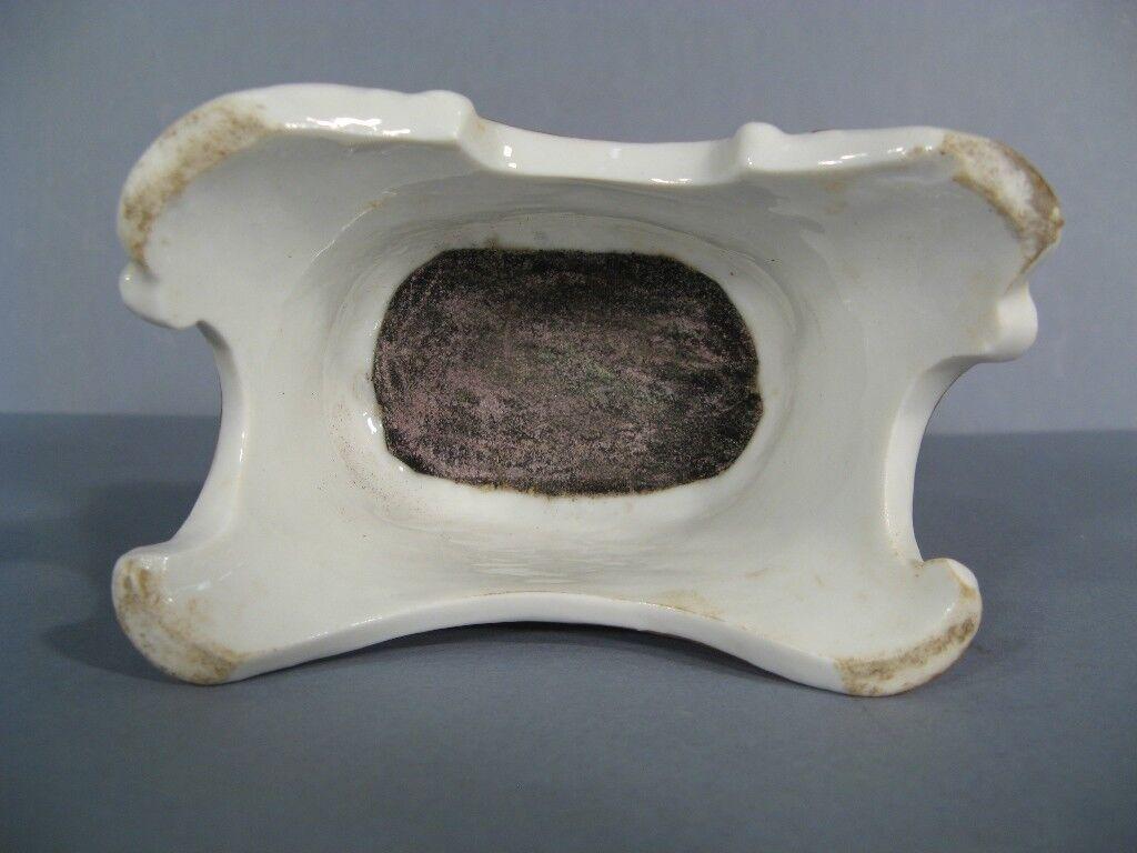 This exquisite late 19th/early 20th century Parisian porcelain match holder, featuring a graceful young woman leaning against a hollowed-out tree trunk, adds a touch of elegance and charm to any home décor. The delicate porcelain craftsmanship and