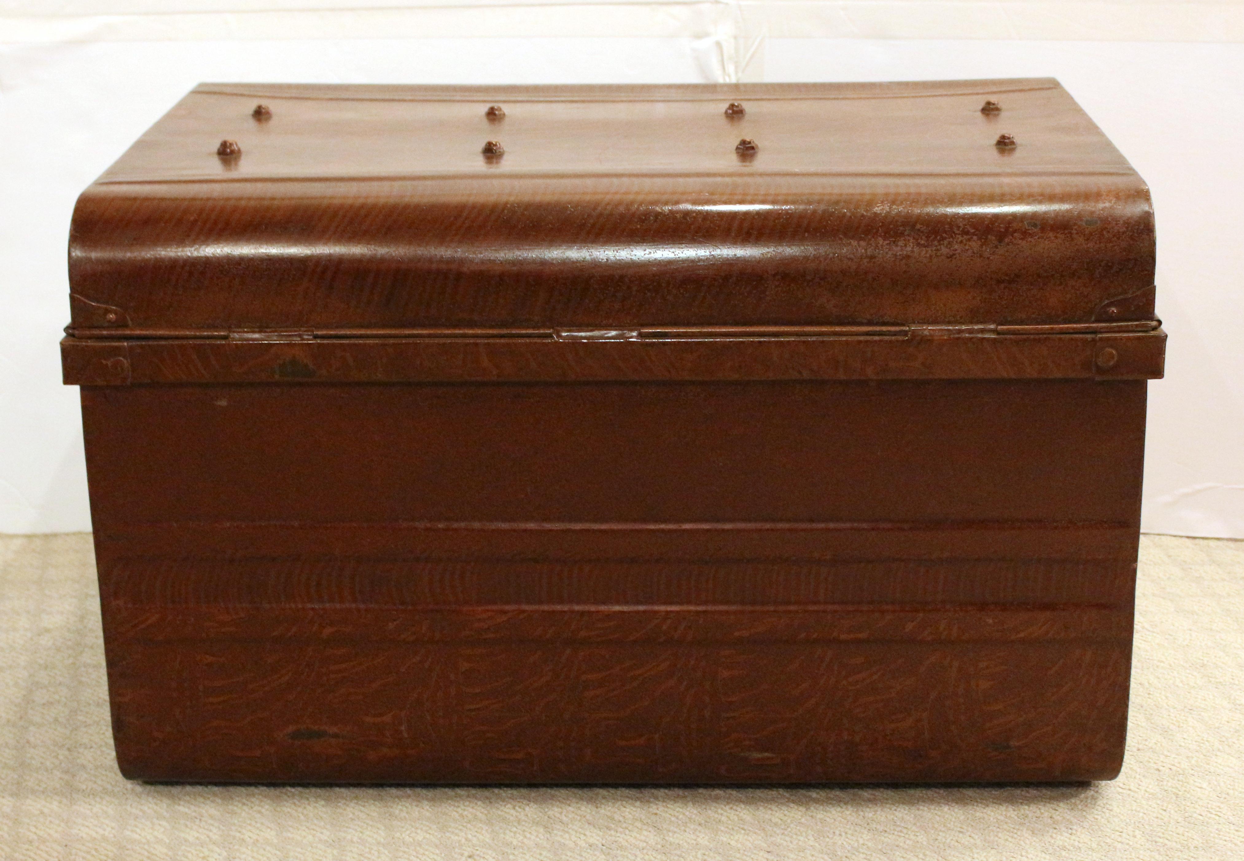 Late 19th to early 20th century steel trunk with original faux bois paint, English. Brass latch lock with shaped backplates. Swing handles. Red painted interior. Ideal as a coffee table. 30 1/2