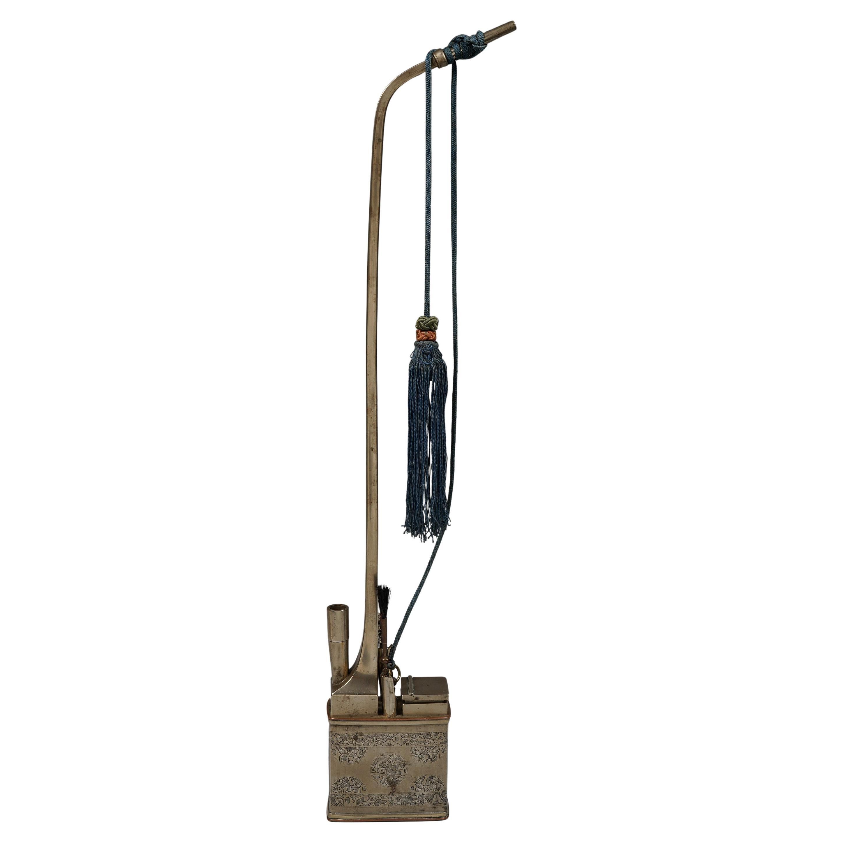 Tobacco Water Pipe with Set of Complete Accessories
China
Late 19th/early 20th century
White metal (baiting), copper decoration, silk cording and tassel
H: 22 in :: 56 cm

Water pipe for smoking opium or tobacco made of baitong, a white metal. The