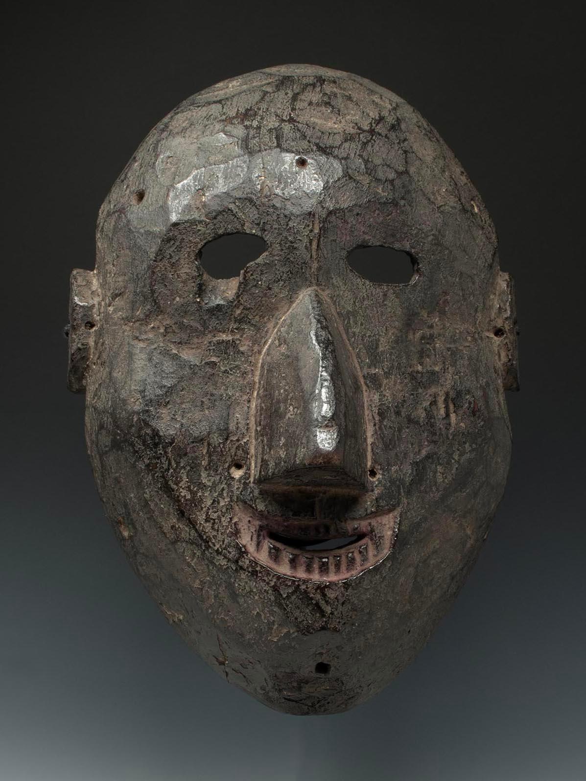 Late 19th-early 20th century Tribal mask, West Nepal

A large mask from West Nepal with a small grin and bared teeth surrounded with pink powder, faint traces of which can also be seen around the eyes. The reverse shows deep adze work and rich