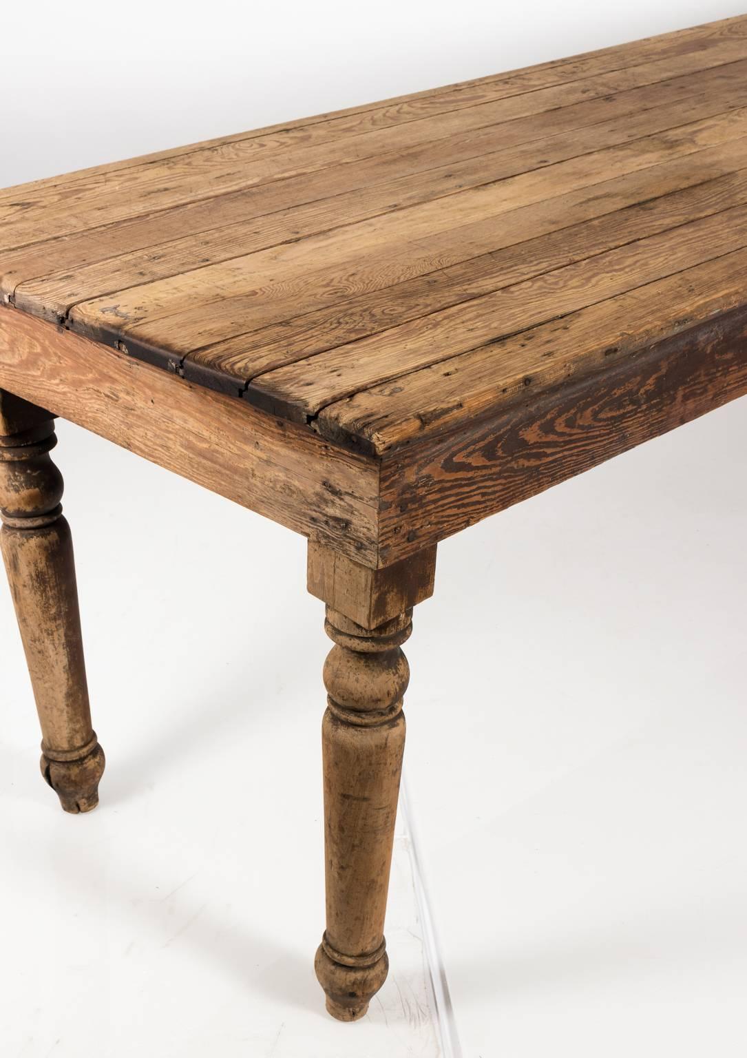 Rustic pine board farm table on ball and ring turned legs with a straight apron, circa late 19th century. This table is also noted for its weathered, rough hewn finish.