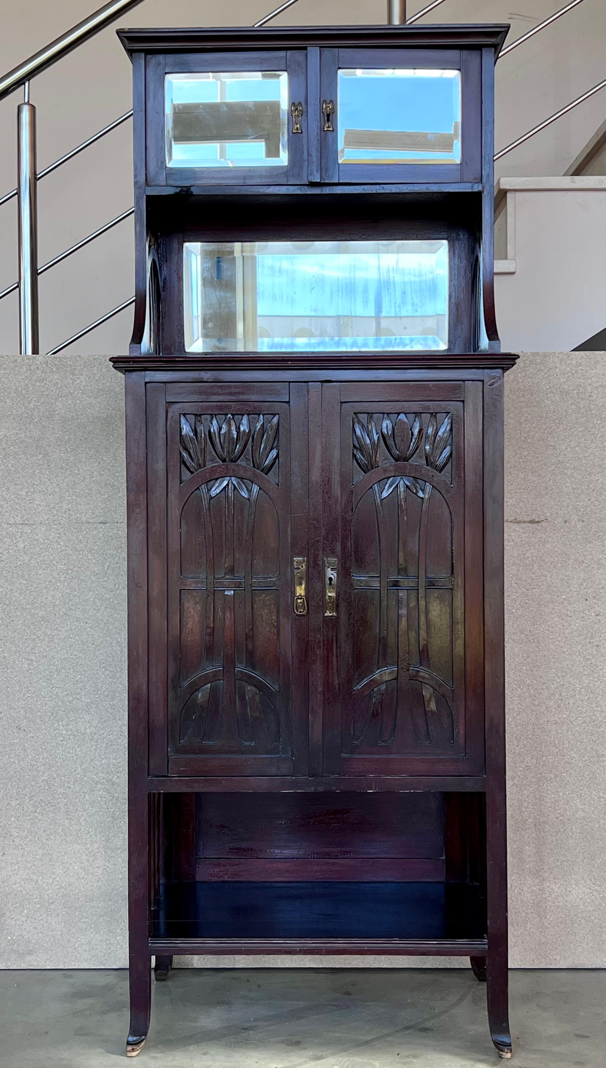 The Vertiko made from walnut with brass fittings, a mirror with facet cut, with typical Art Nouveau ornamentations.  In good restored condition with the original glasses and mirror.