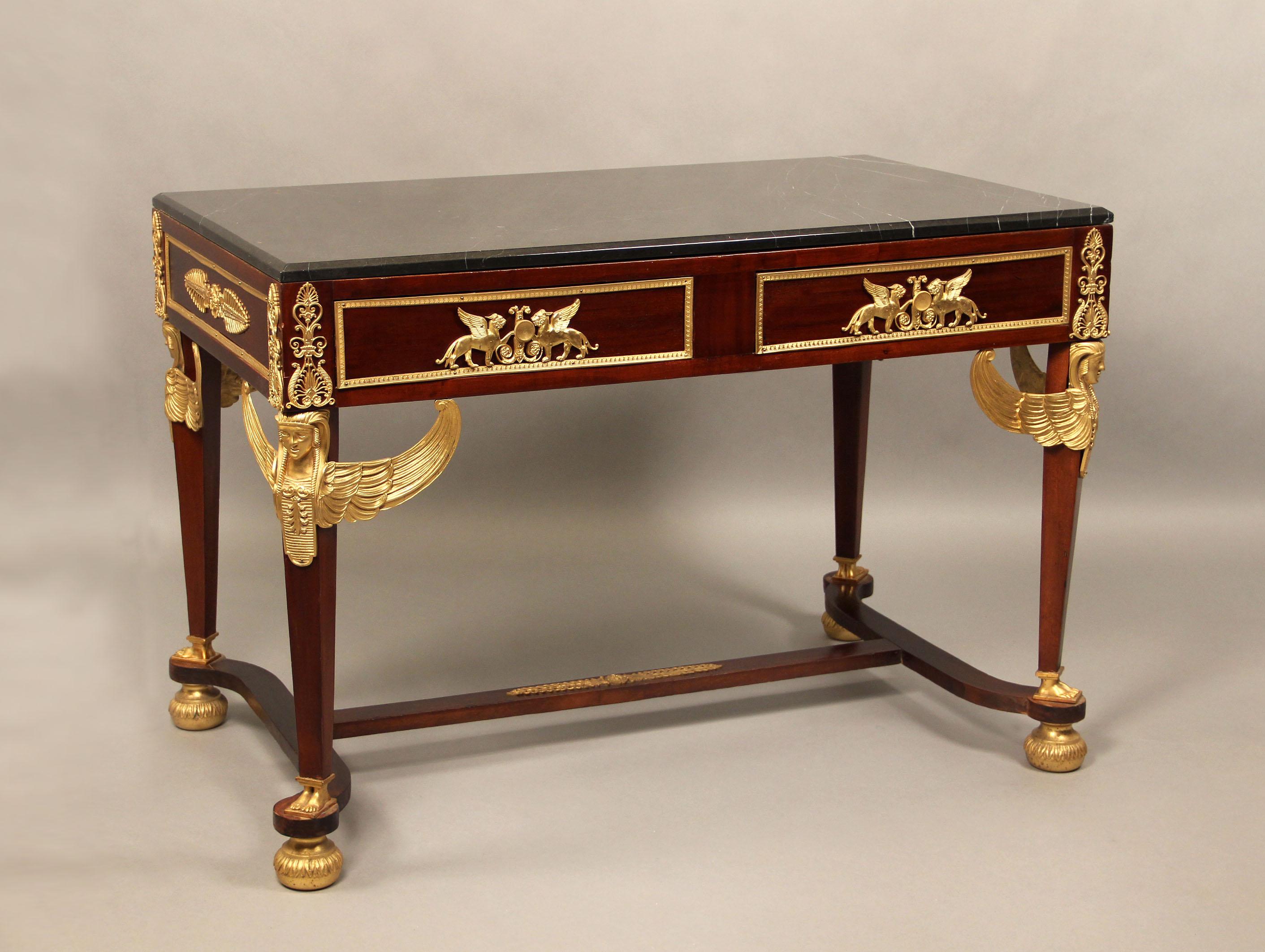 French late 19th gilt bronze-mounted mahogany center table in the Empire revival style.

With rectangular black marble top with a molded edge, above a pair of frieze drawer, supported on winged-female term support, 