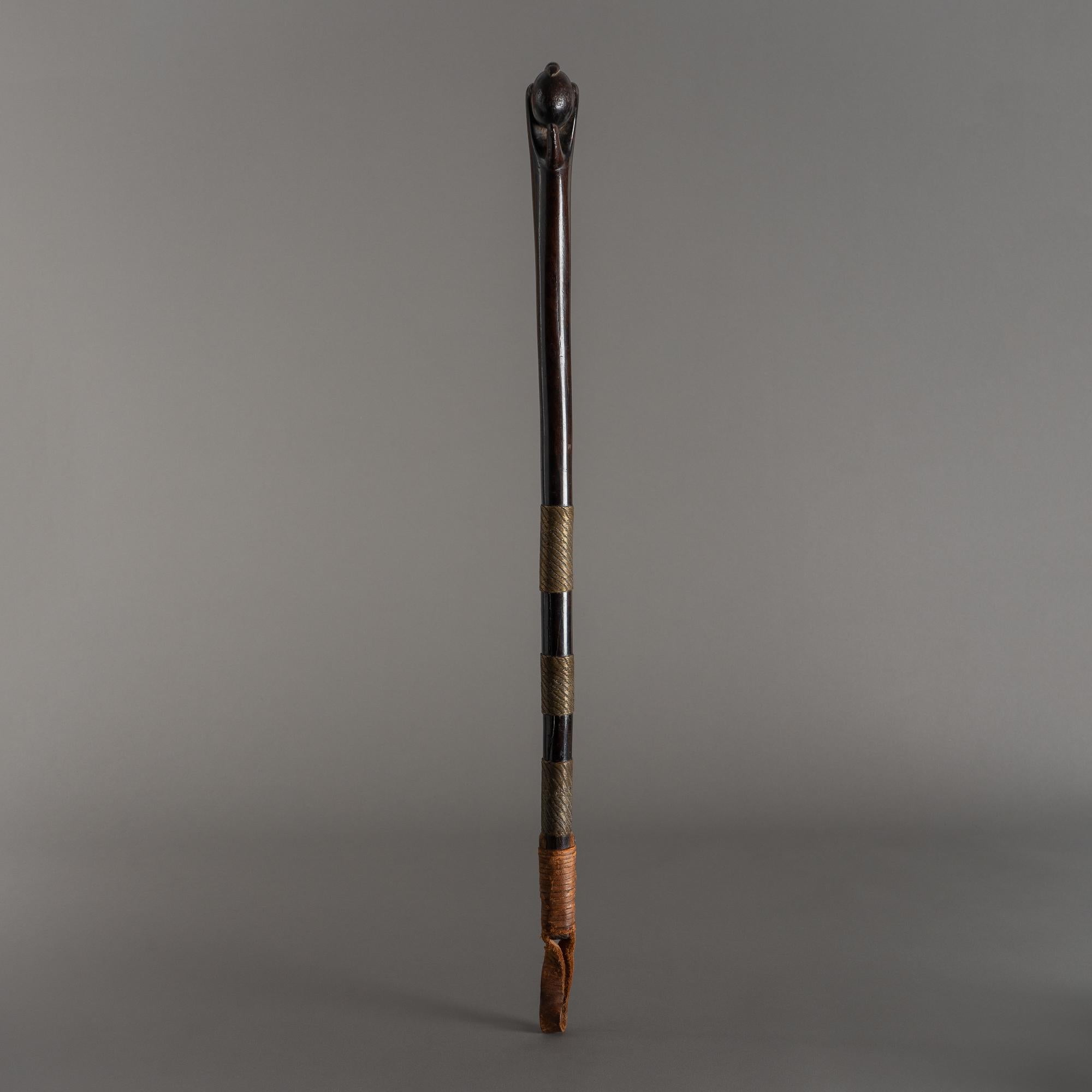 This artfully carved hardwood stick features a four-fingered claw grasping an egg, symbolizing the fragile and somewhat mysterious nature of life. Graced with a dark patina, the shaft is wrapped with three wide bands of dense brass wirework,