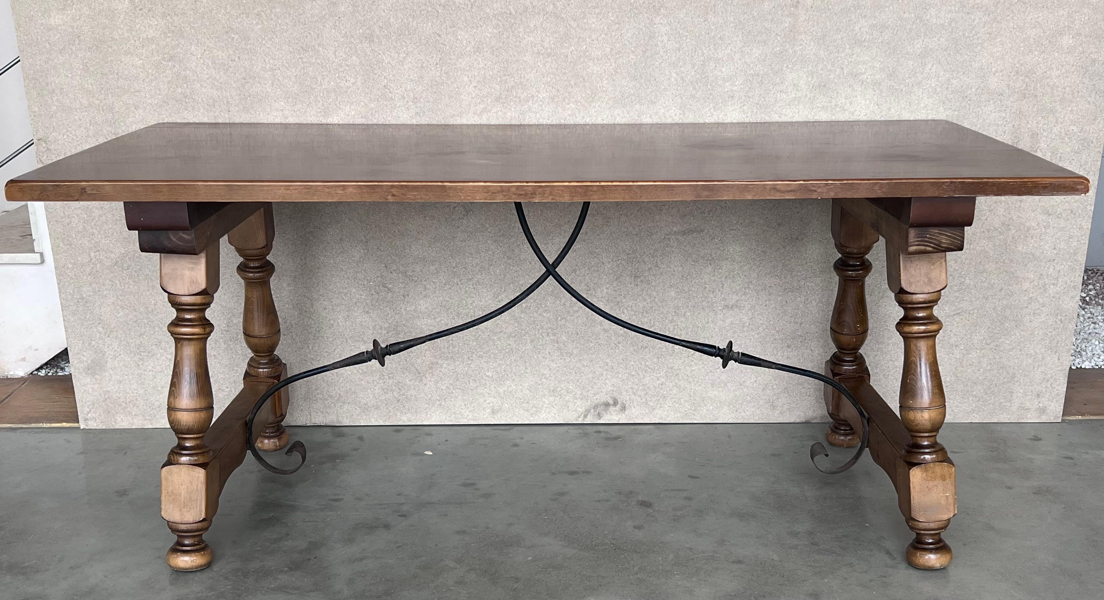 Ein spanischer Fratino-Esstisch mit handgefertigter schmiedeeiserner Bahre aus dem späten 19. Dieser spanische Holztisch hat eine robuste rechteckige Platte, die auf einem exquisiten Sockel aus geschnitzten Beinen ruht, die durch eine seitliche