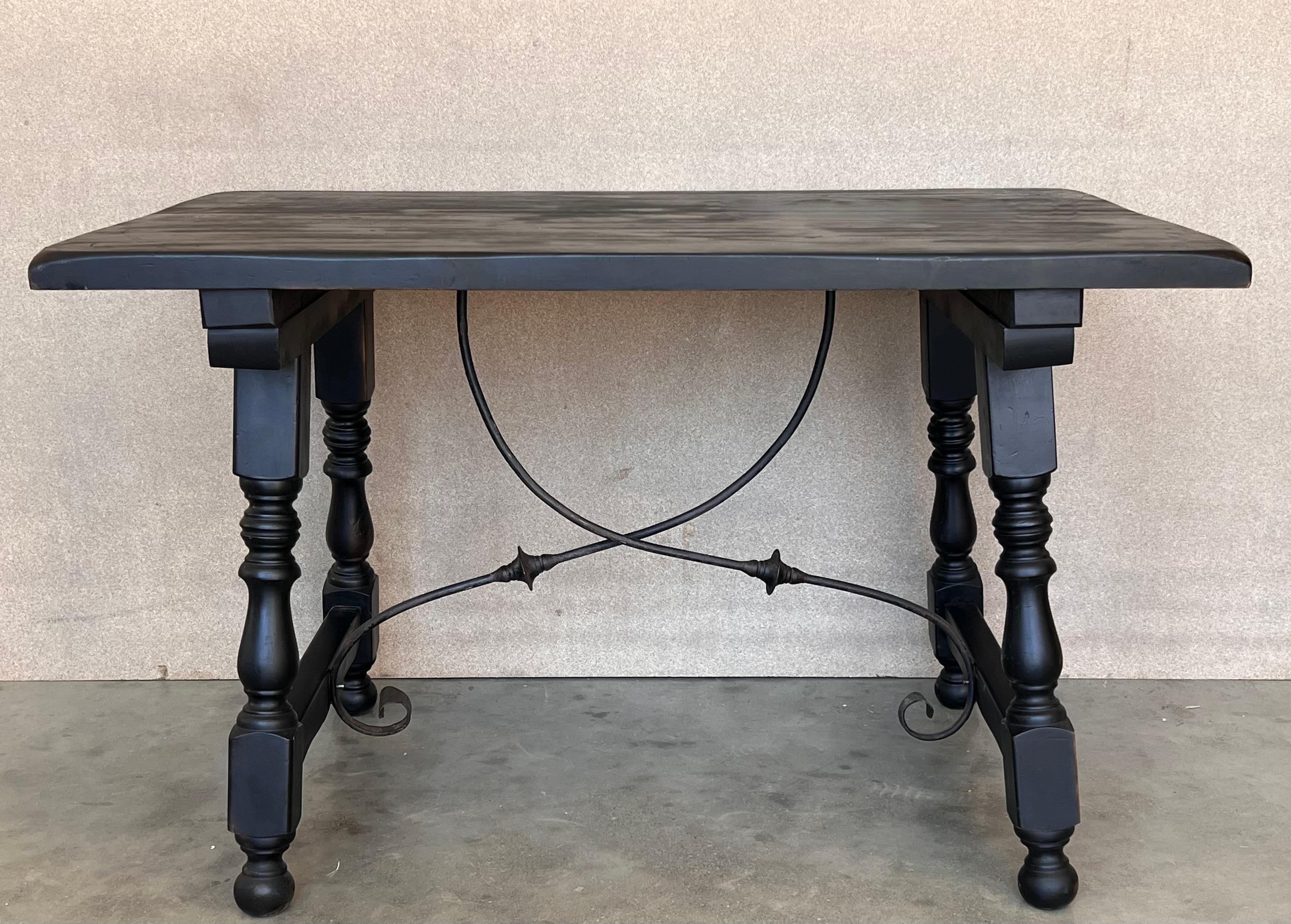 A Spanish Fratino dining table with hand made wrought-iron stretcher from the late 19th century. This Spanish wooden table features a sturdy rectangular top sitting above an exquisite base made of splayed carved legs connected to one another with a