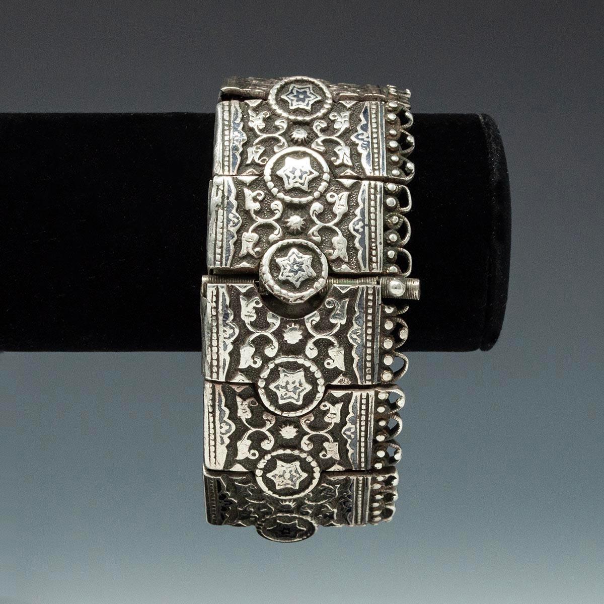 Usually, this segmented design is fashioned into belts, but here it is as a beautiful rare bracelet. The 13 niello and silver interlocking segments are threaded on a band of leather for flexibility; there is a pin closure. It measures 2.5 inches