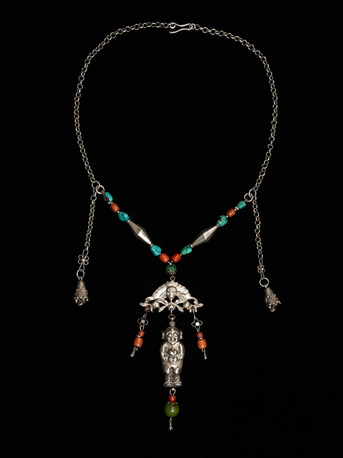 Late 19th to early 20th century silver baby amulet necklace, CChina

A wonderfully balanced silver chain necklace with coral and turquoise beads is anchored by a bat, from which dangles a baby amulet holding what appear to be peaches. The inner