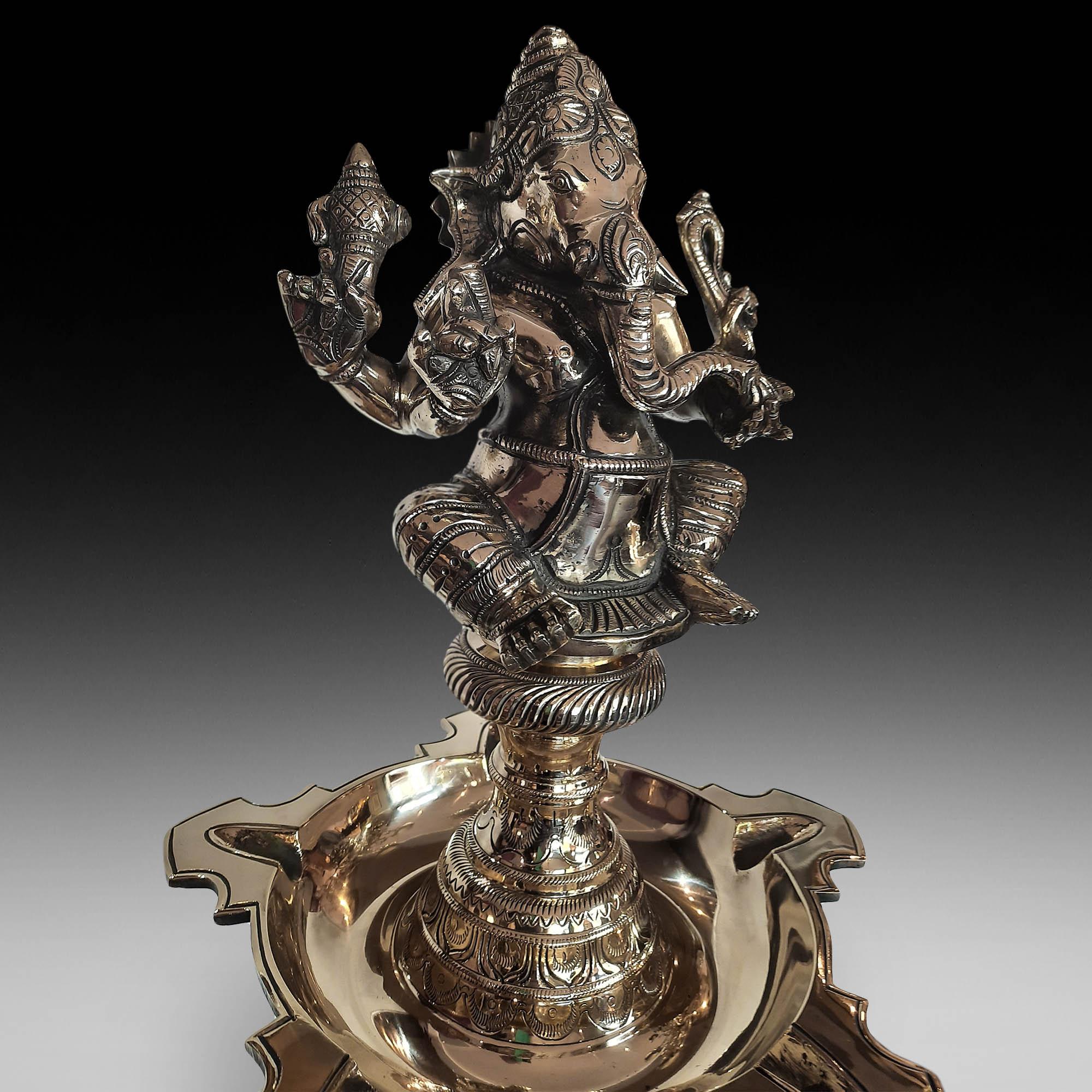Late 19thC Indian brass pedestal temple censer, surmounted with a figure of Ganesh over an oil dish and multi-knopped column chased with foliate details, over a dished base 63