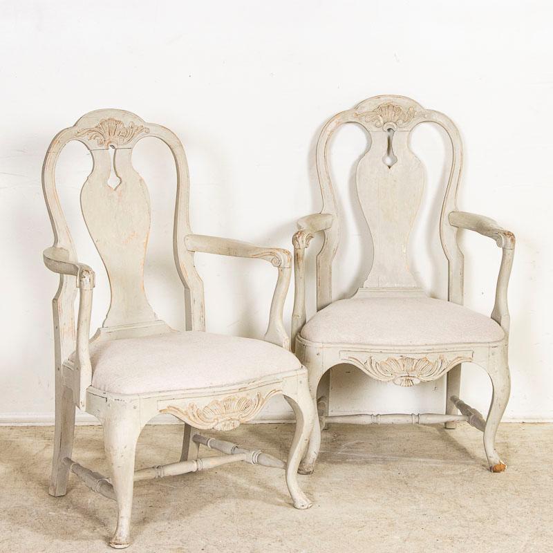The gracious curves seen in these two arm chairs are reflective of Sweden's love of Rococo styling. Curved backs, cabriolet legs, turned spindles as stretchers and carved details all combine for a romantic look to each chair. The soft, dove gray
