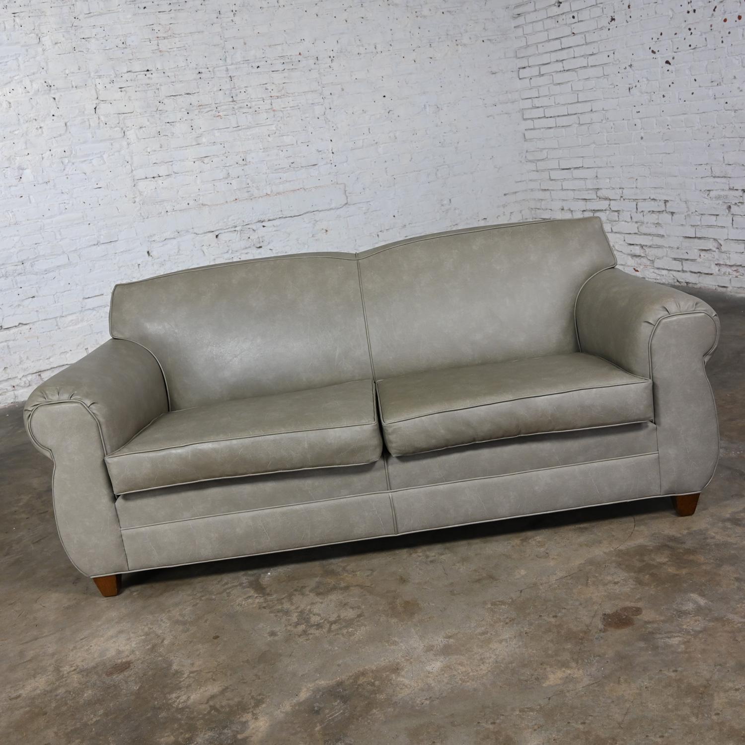 Handsome vintage taupe gray faux leather upholstered Bridgewater style sofa with tight back, two loose seat cushions & square tapered wood feet. Beautiful condition, keeping in mind that this is vintage and not new so will have signs of use and