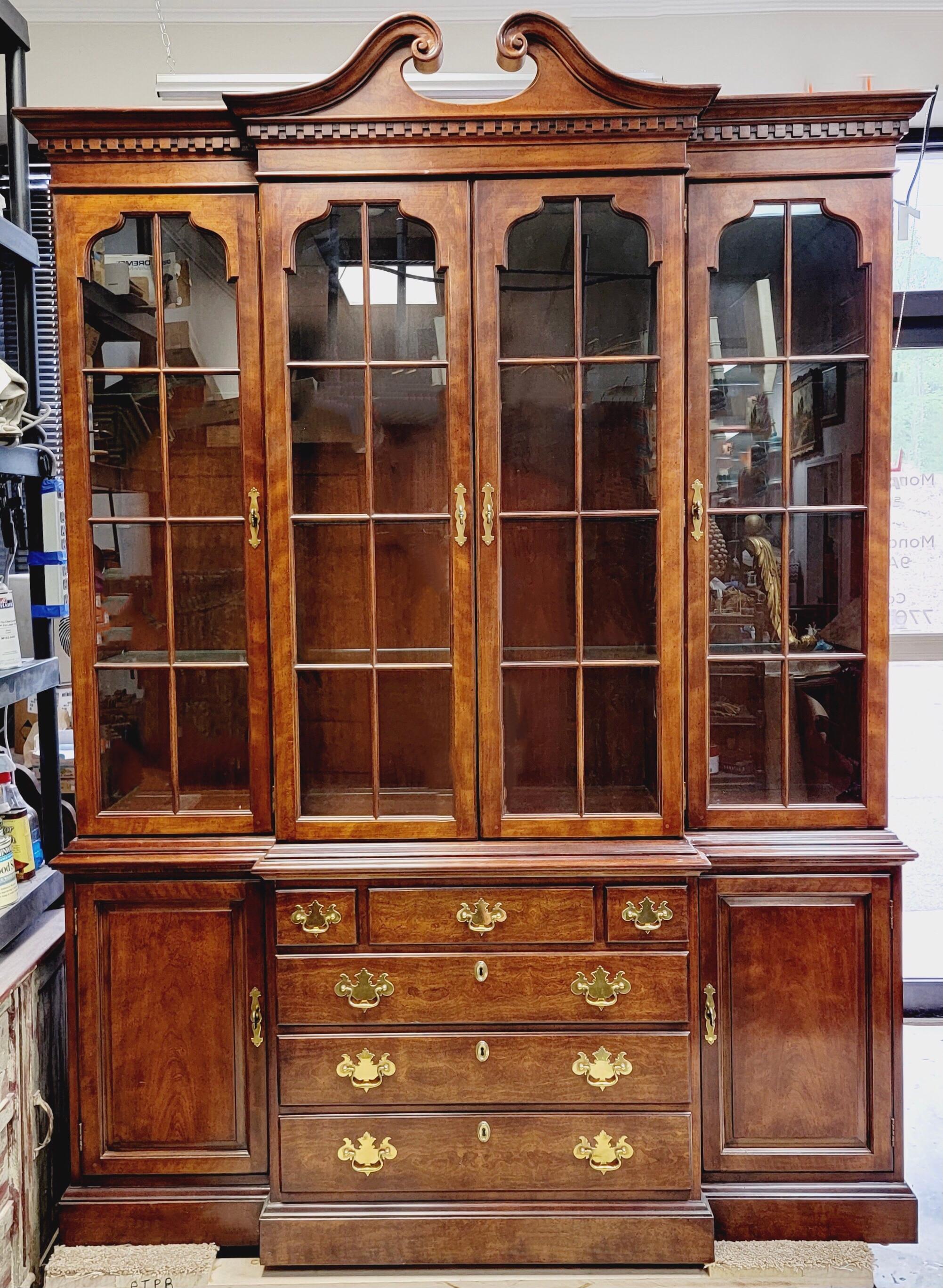 This is a classic Chinese chippendale style carved mahogany cabinet by Henredon. It is a two part cabintet. There are three glass shelves in all three sections of the top. The glass portion has recessed lighting. The bottom, conversely, has wooden