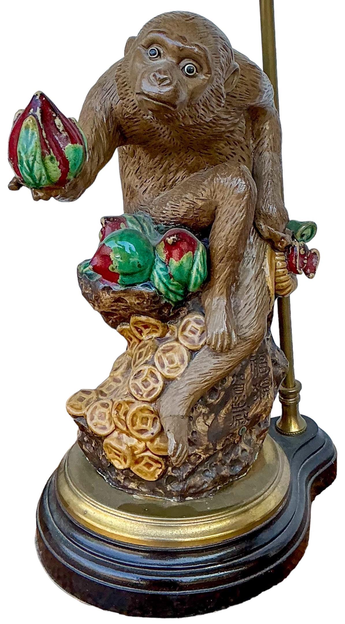 This is a late 20th century Chinese Export style table lamp depicting a monkey with pomegranites . It is mounted on a wood base with brass accents. It is in very good condition.