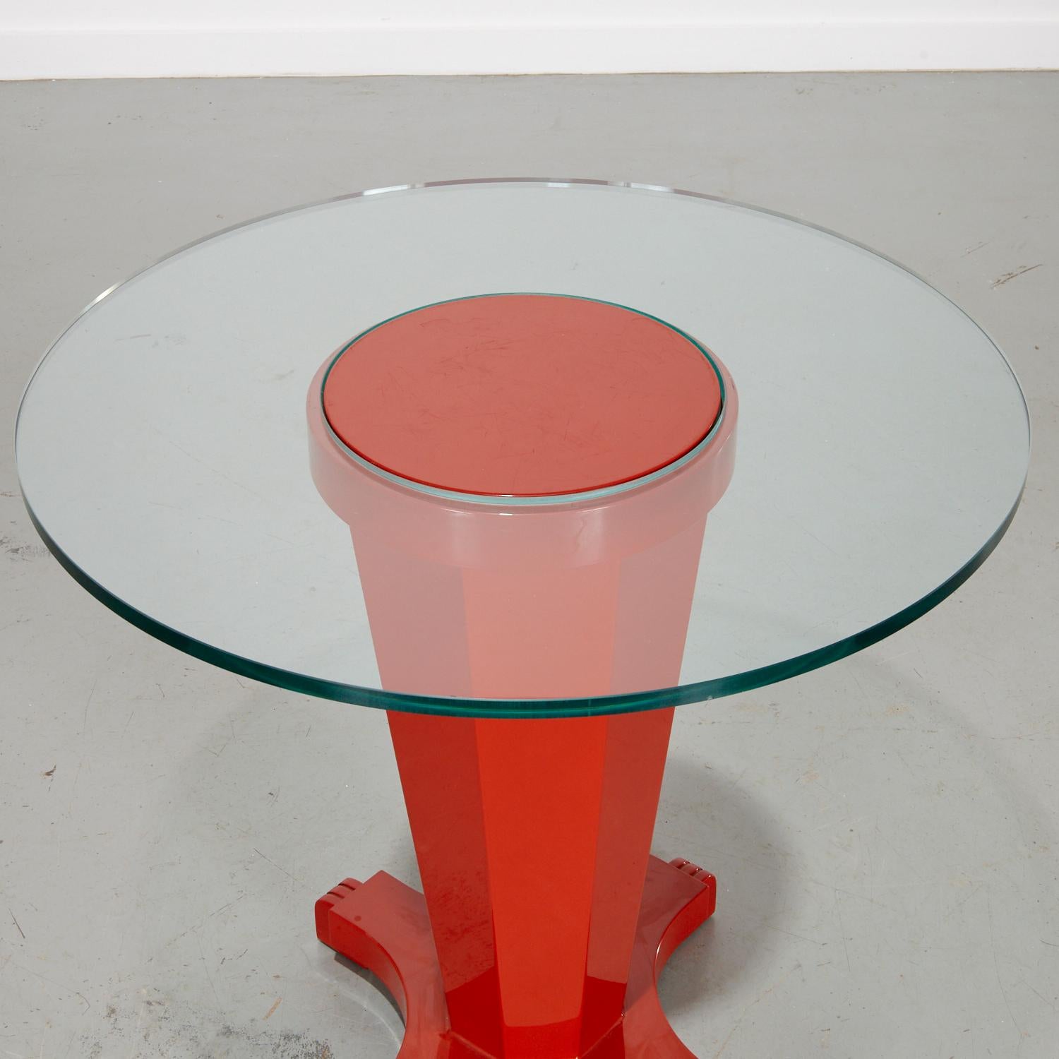 20th c., contemporary side table with a distinctive design in vermillion lacquered wood, .75-inch plate green doughnut shape glass.

The table features a vibrant red, fluted pedestal base with an elegant art deco influence. The base includes a
