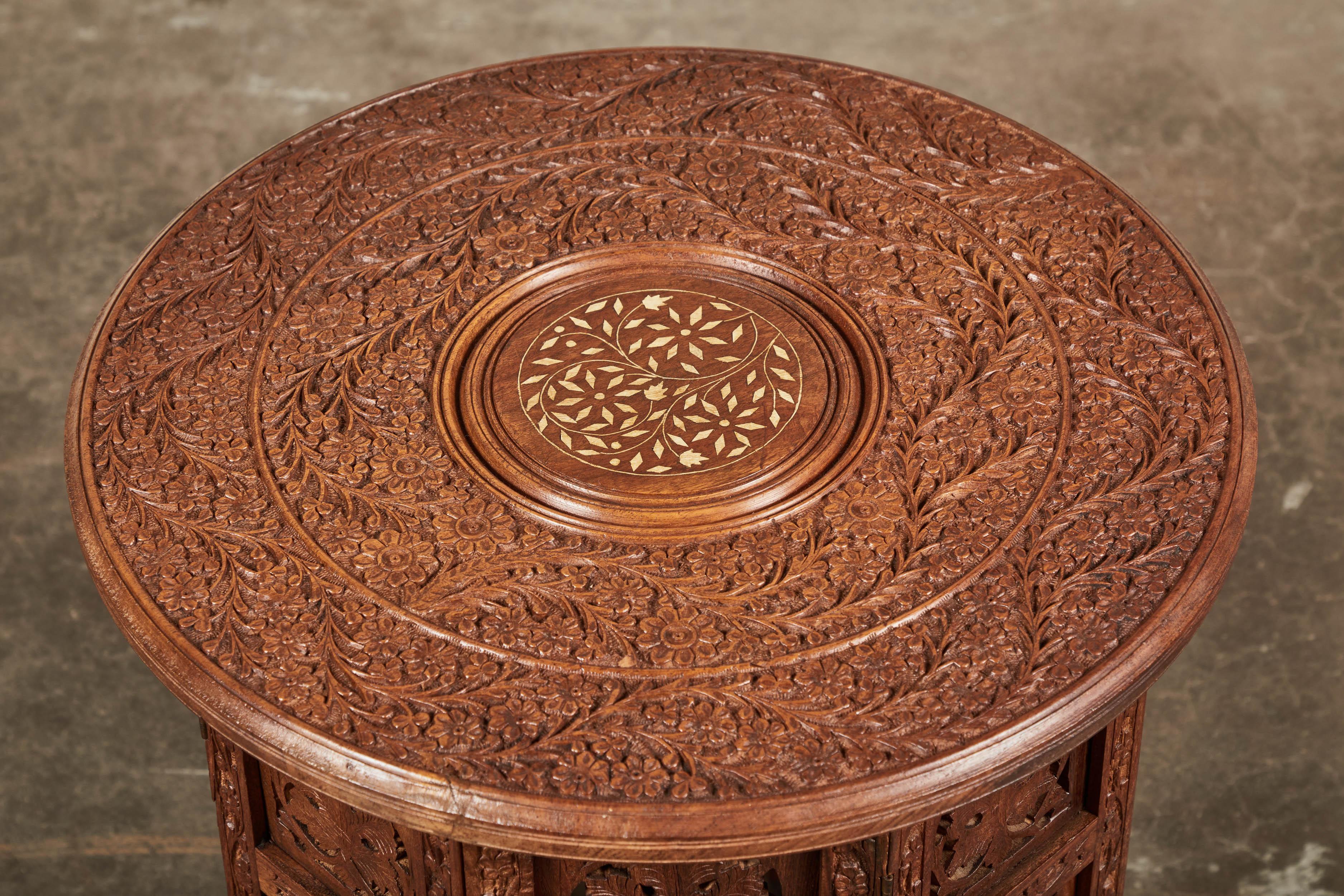 Handmade and hand carved octagonal-base Indian side table. Top features a small bone inlay center medallion, on a carved, folding base, late 20th century.