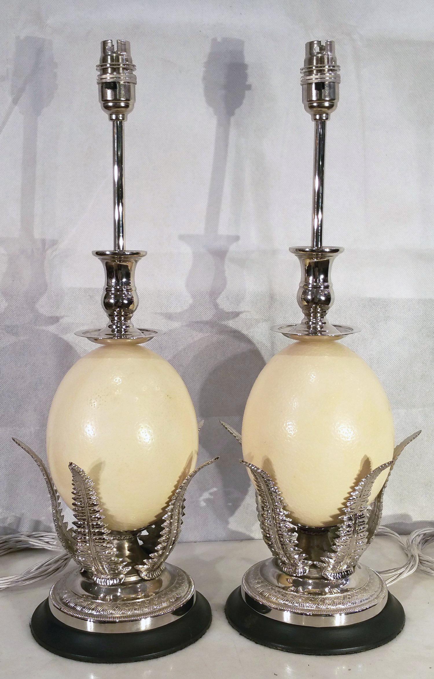 This highly decorative and unusual pair of Ostrich Egg table lamps has been designed in the Georgian style and rest on a bed of silver plated shaped fern leaves, on a circular base. The lamps feature an elongated neck with a bayonet styled light