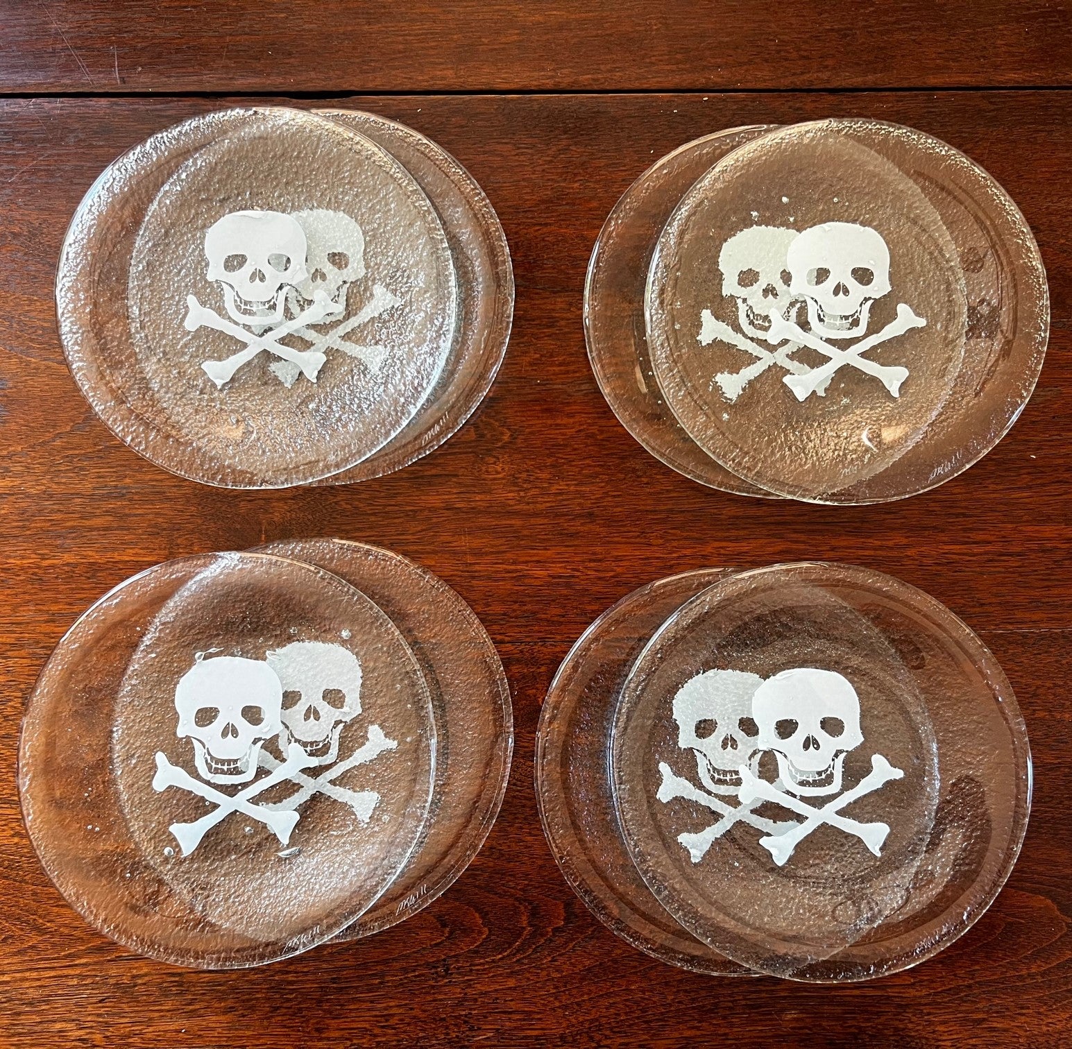 Late 20th C., a set of 8 seeded glass side plates with a white skull and crossbones design. These plates are substantial. The skull and crossbone design is incorporated into the seeded glass, not printed on.

Dimensions:
8