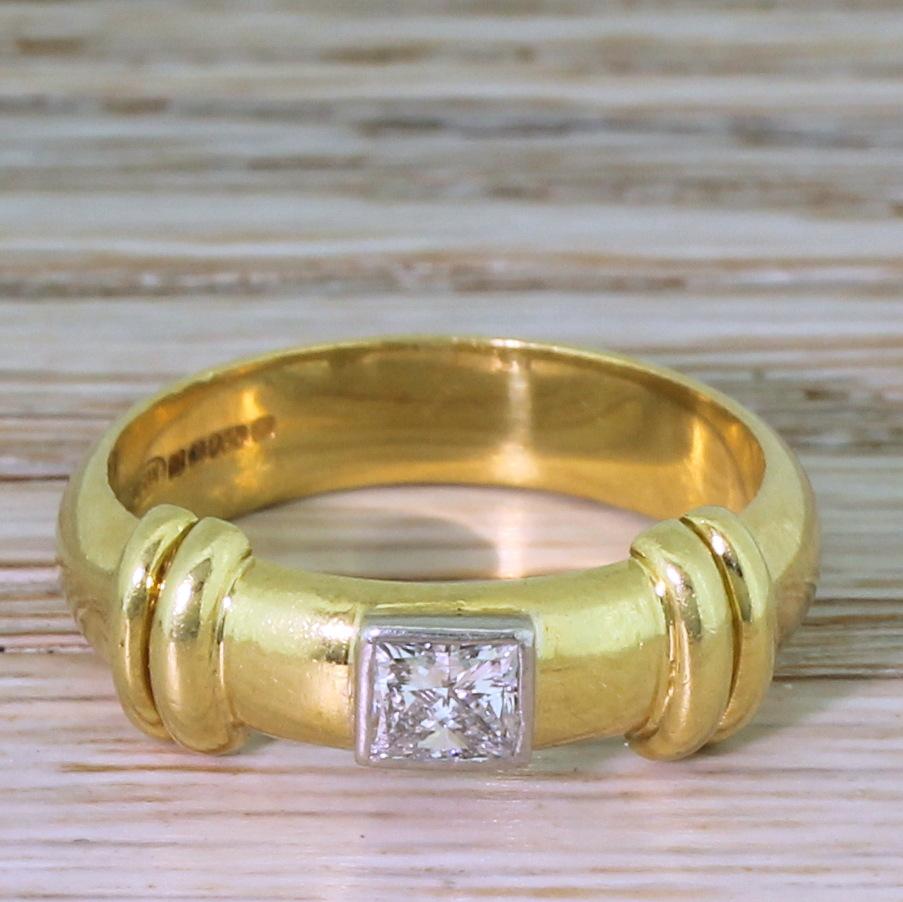 A fine modern princess cut diamond ring. The slightly rectangular shaped diamond is set laterally in a rubover setting in a heavy weight D-shaped yellow gold shank, with fluted gold embellishments at either side of the stone. A ring that would work