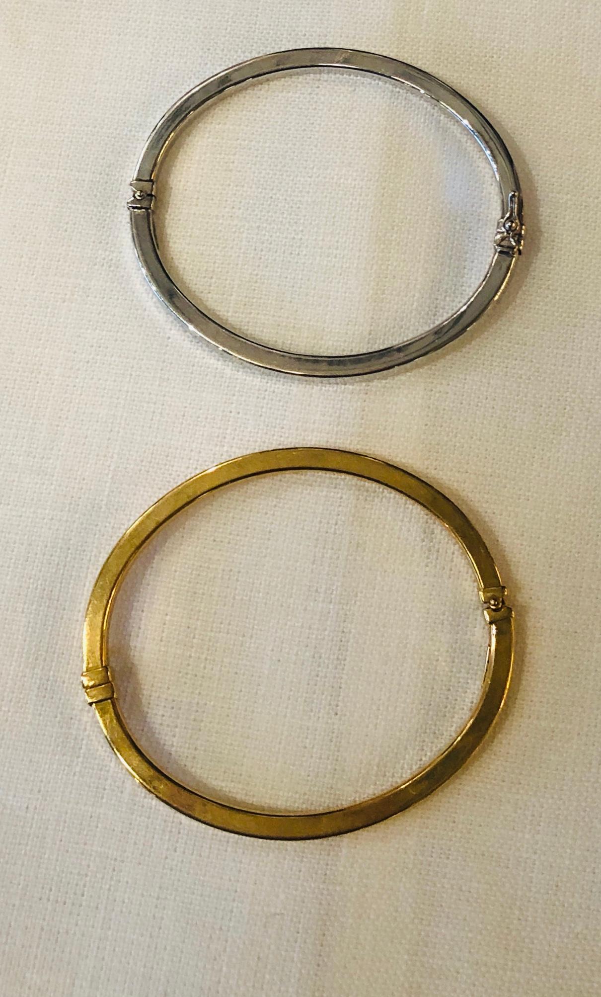 Offered are two late 20th century Italian stamped 18-karat one white and one yellow gold bangles / bracelets with clasps and spring action that were made for Neiman Marcus. These Minimalist bangles are great on their own or when stacking multiple