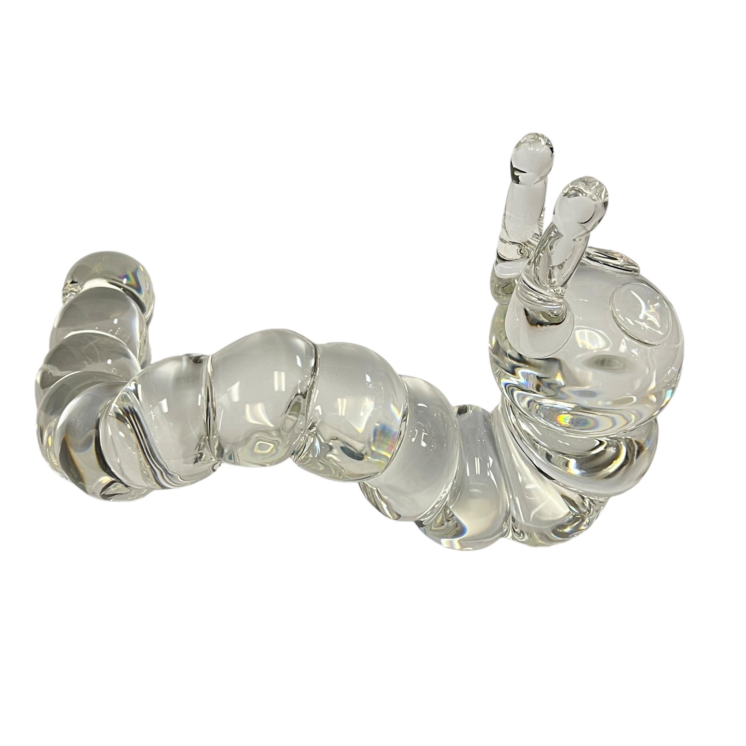 A Late 20th Century American Crystal Caterpillar Designed by Peter Yenawine, for Steuben Glass depicting an inching caterpillar with outstretched antennas and applied eyes gives a realistic movement to the sculpture. The caterpillar is signed on the