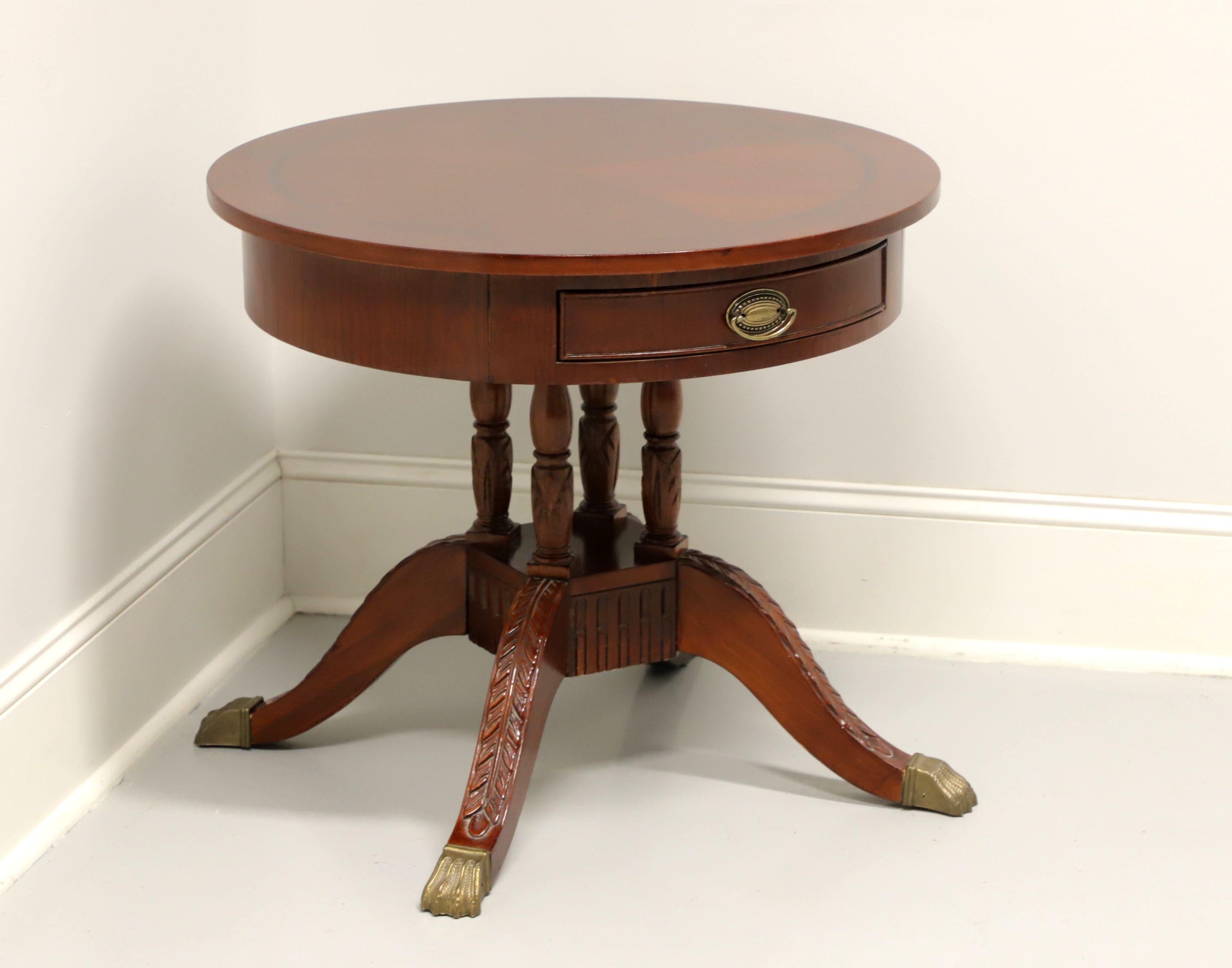 A Georgian style round drum table, unbranded. Cherry wood with banded & inlaid top, brass hardware, carved birdcage pedestal base and four acanthus leaf carved legs with brass paw caps. Features one small drawer. Made in Asia, in the late 20th