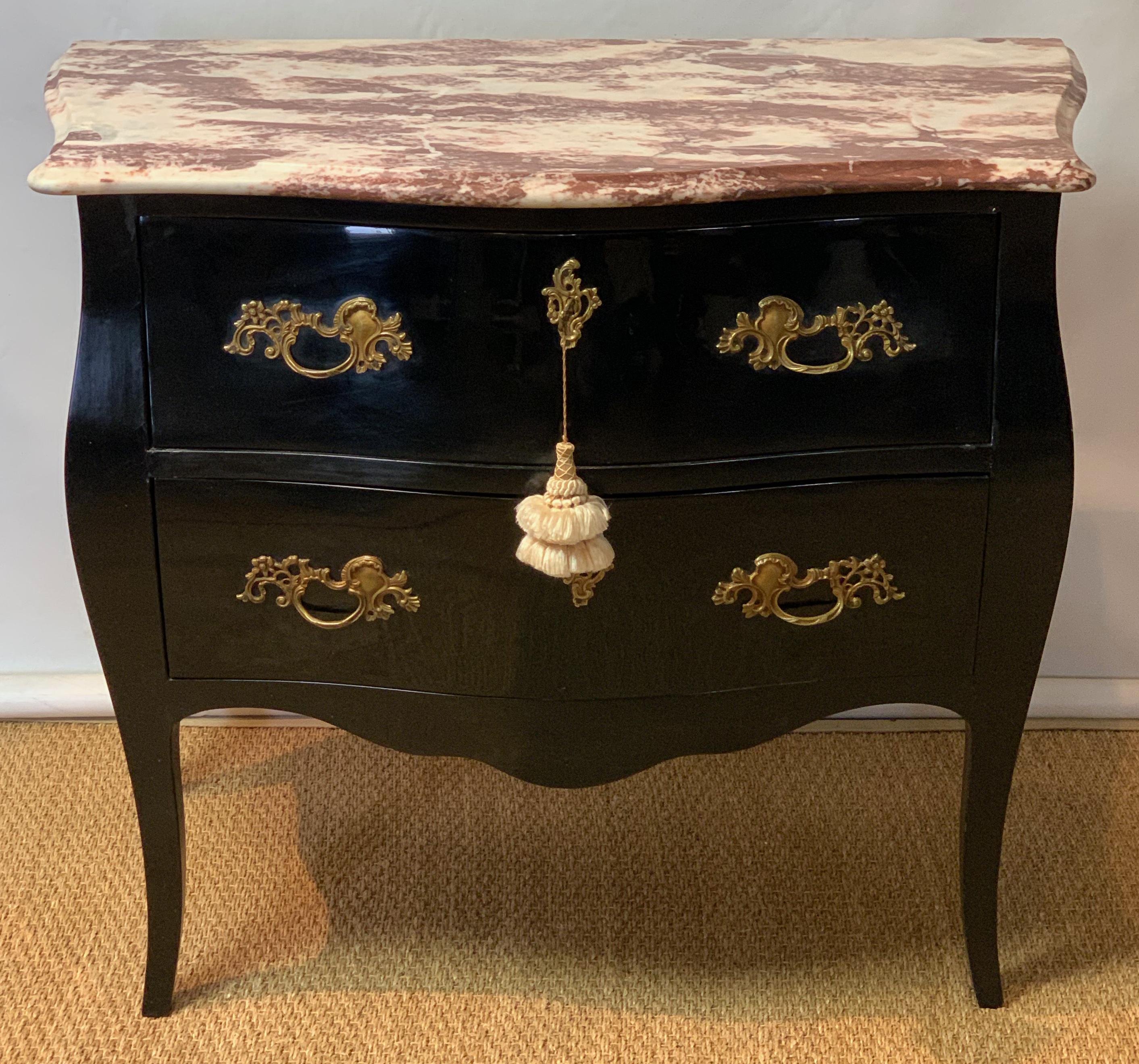 A late 20th C. two drawer black lacquer Bombé commode with gilt brass pulls and a rouge marble top.