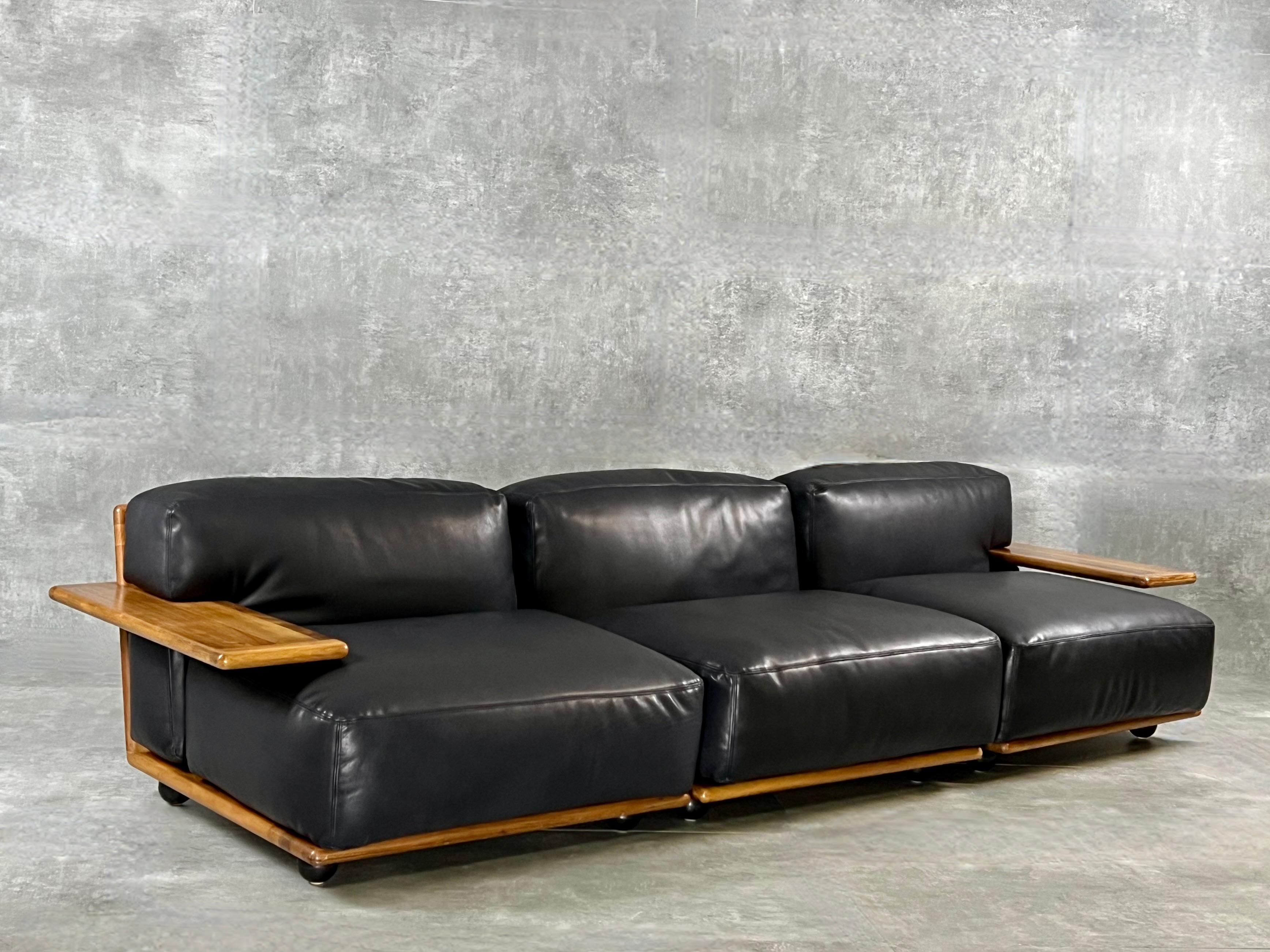 Stunning Pianura sectional seating group of three pieces. Walnut wooden structure with high comfort black leather cushions. Designed by Mario Bellini for Cassina in the 1970's.
The walnut has signs of use that matches the age and wear.  Still very
