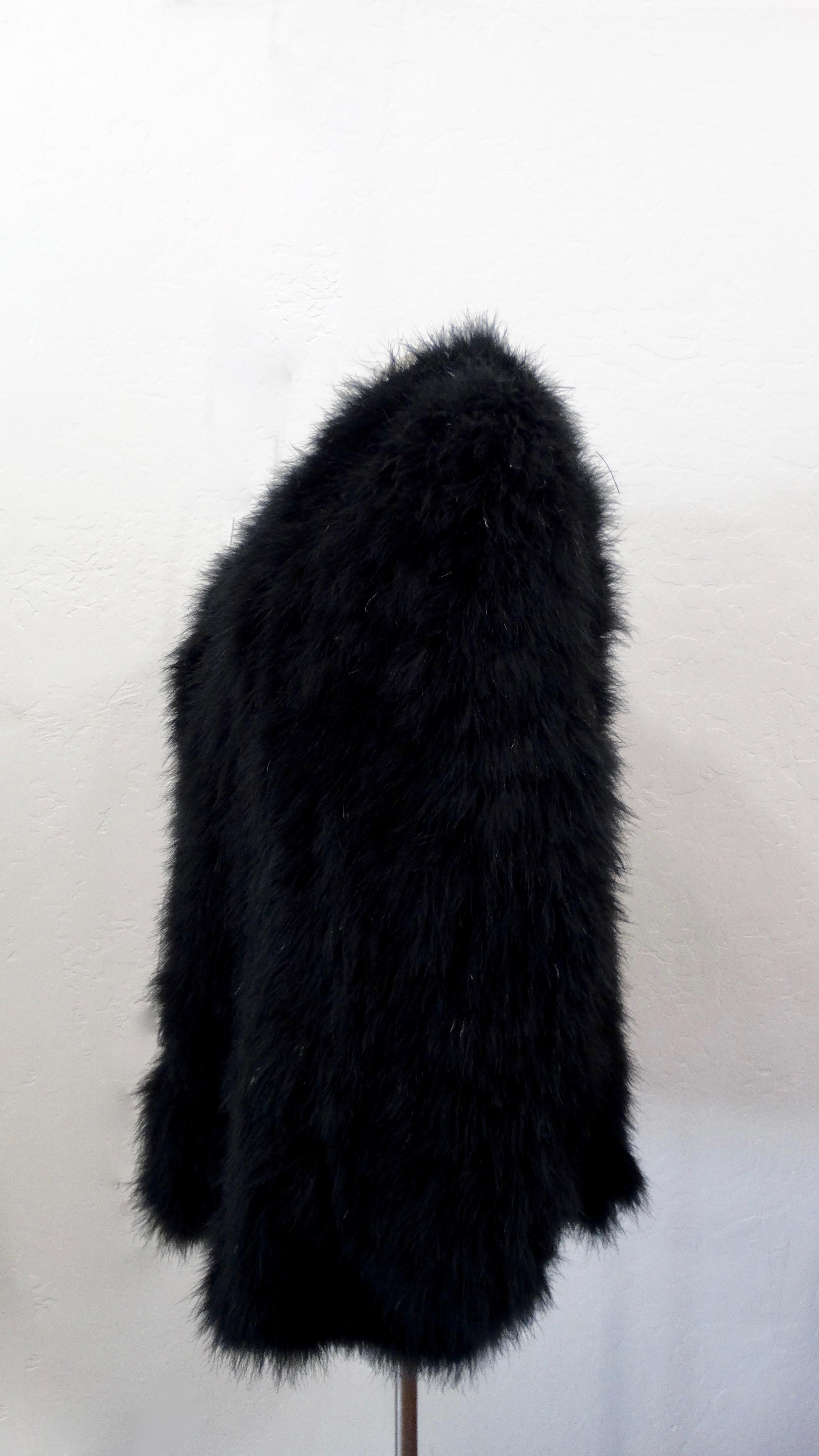 Take on the cold weather in style! Circa late 20th-century, this mid-length coat is hand-crafted from soft black Marabou feathers and features inseam pockets. Interior is fully lined in black fabric (rayon & acetate). Perfect for a night out over