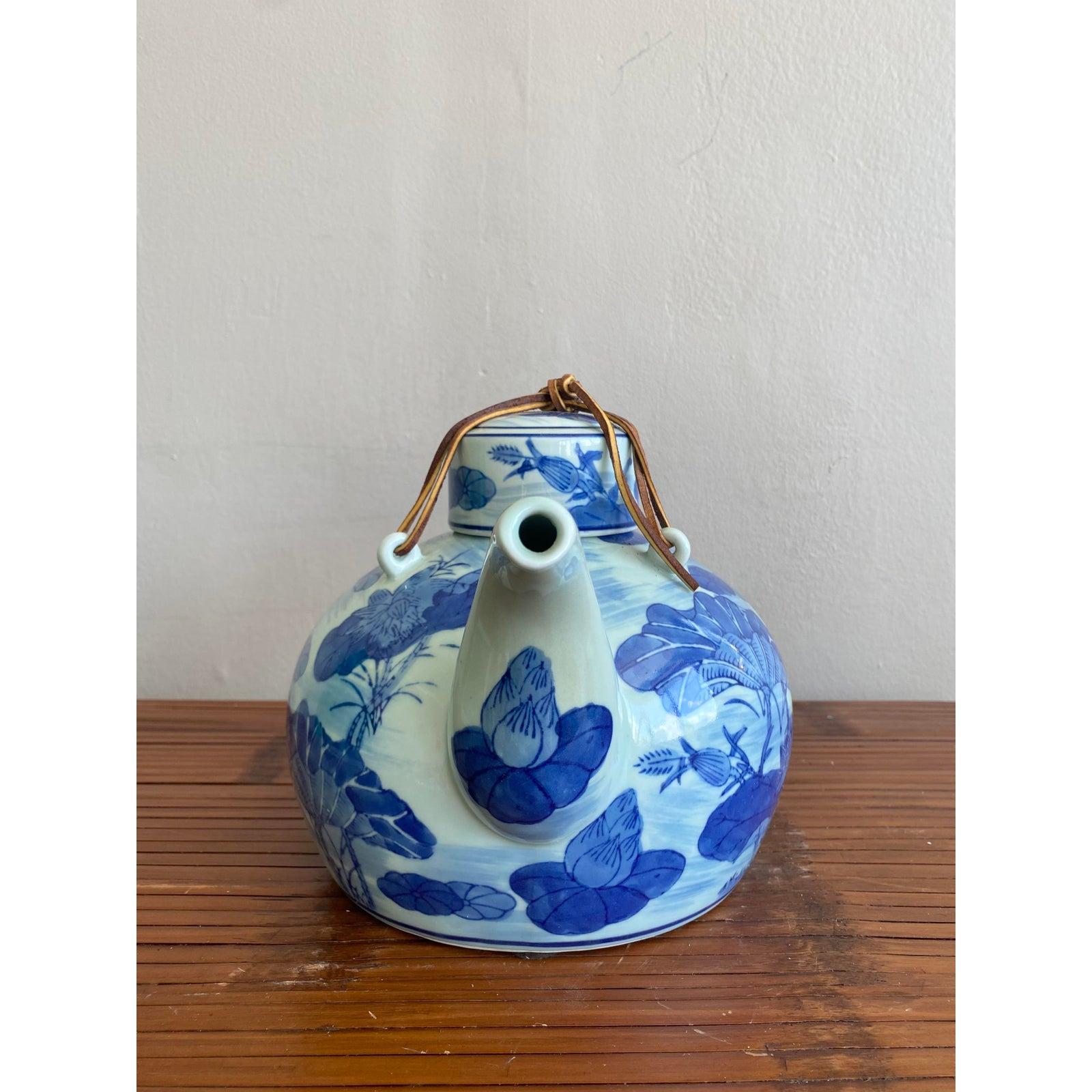 Questa elegante teiera cinese in porcellana presenta una classica forma arrotondata, splendidamente dipinta a mano in un ricco blu cobalto con una serena scena di stagno di loto. Gru e lussureggianti foglie di loto danzano sul morbido terreno color