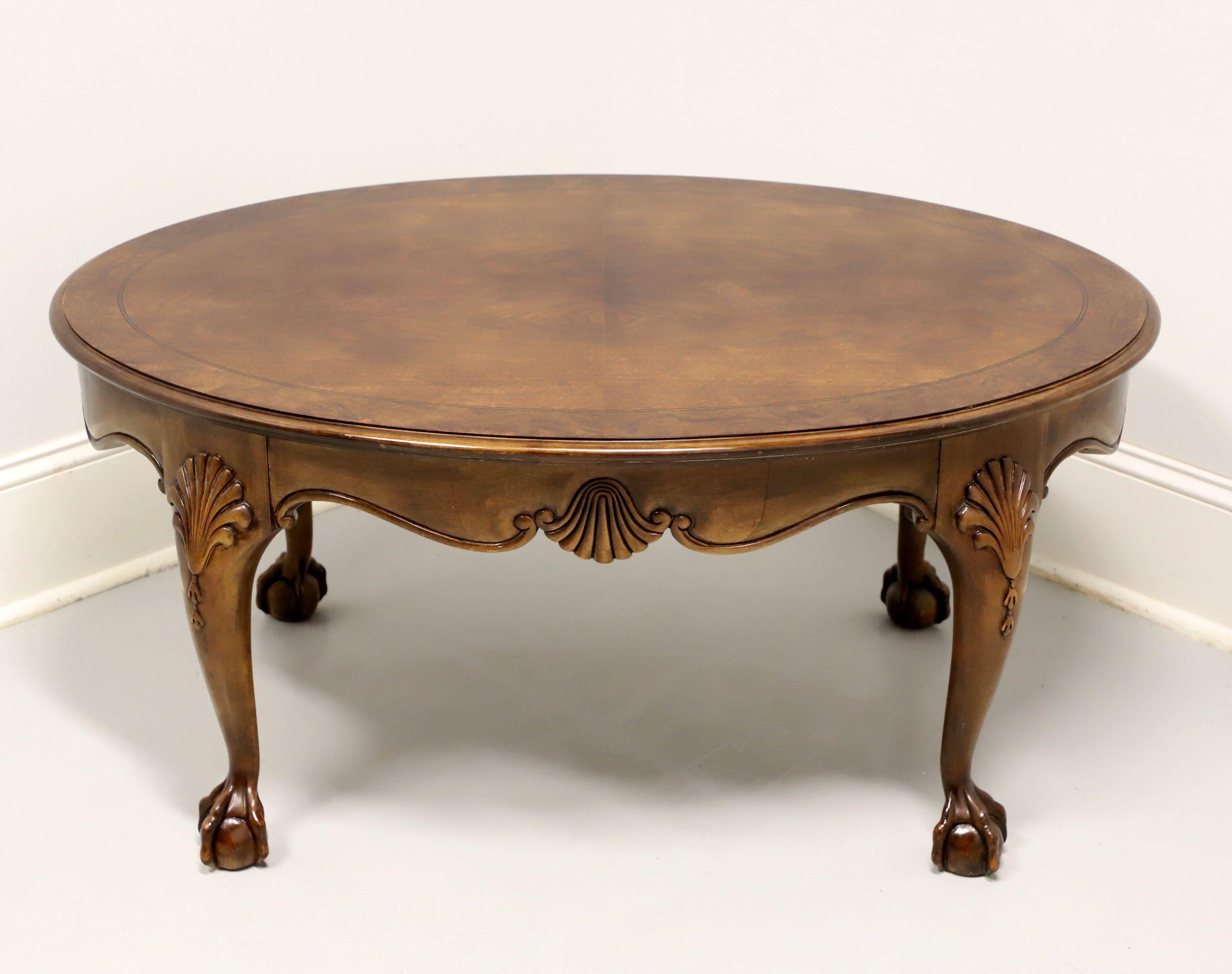An oval Chippendale style coffee table, unbranded, similar quality to Drexel or Thomasville. Walnut with bookmatched & burlwood banded top, decorative fan carved to apron & knees, and ball in claw feet. Made in the USA, in the late 20th