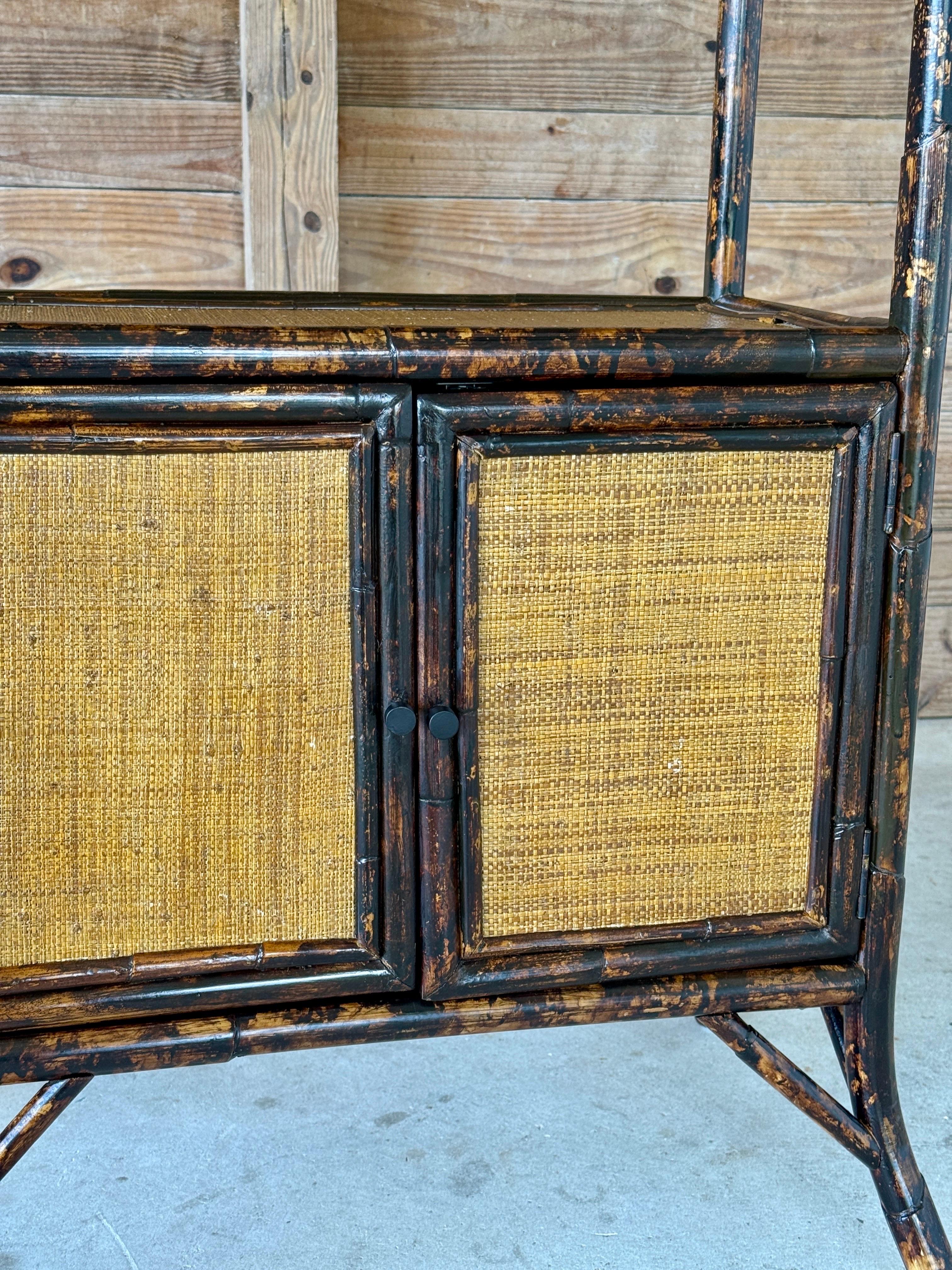 Charmante étagère de la fin du XXe siècle, de style Coloni britannique, dotée d'un cadre en faux rotin de tortue et de surfaces en toile d'herbe tissée. Cette pièce offre à la fois des étagères ouvertes et une armoire à double porte en dessous, ce