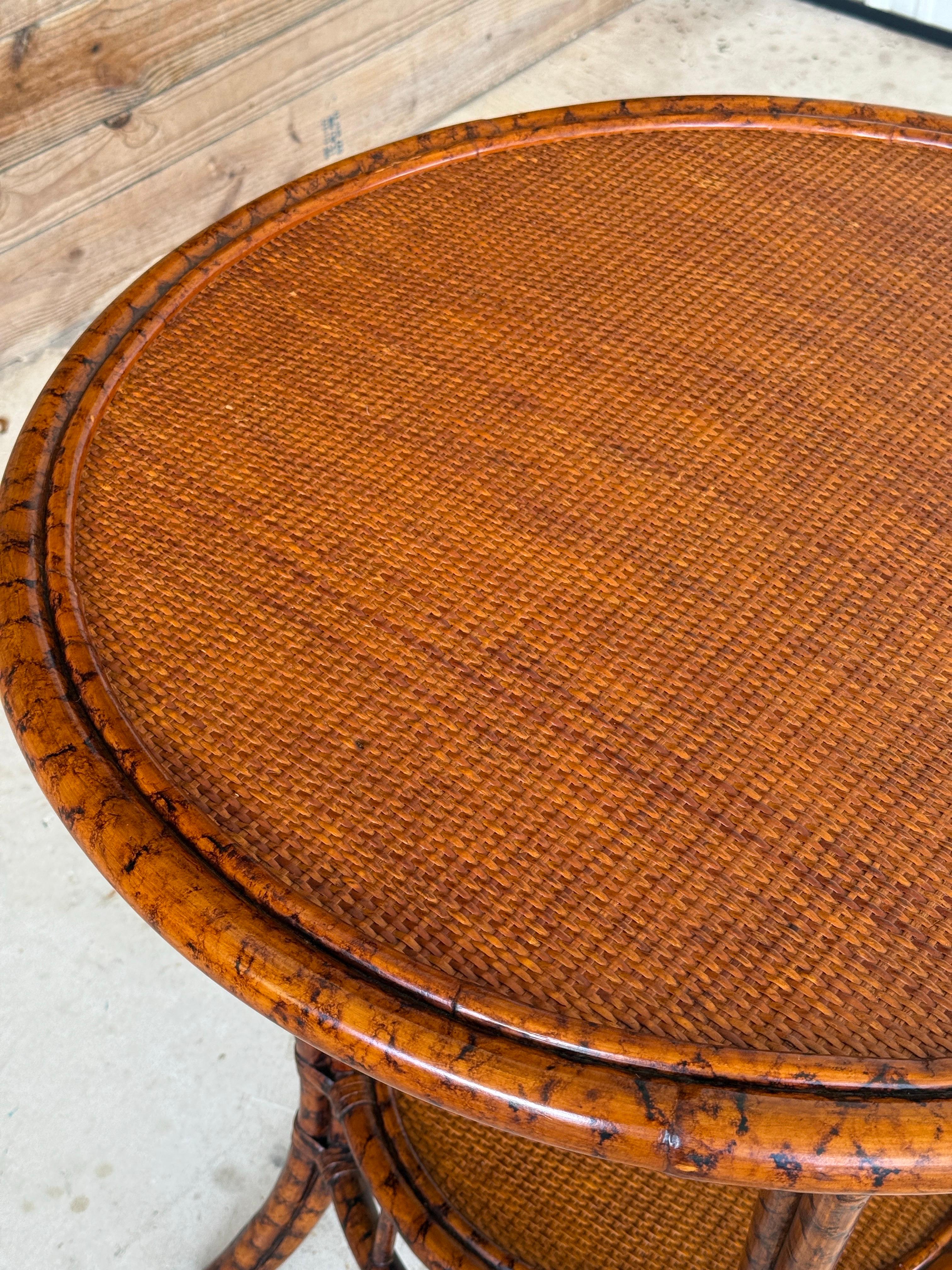 A stylish Late 20th Century rattan center table by PTMC, designed with a warm tortoise finish and woven cane lower and upper shelf. Its round form and gently flared legs give it a balanced coastal-tropical feel, making it versatile as a center