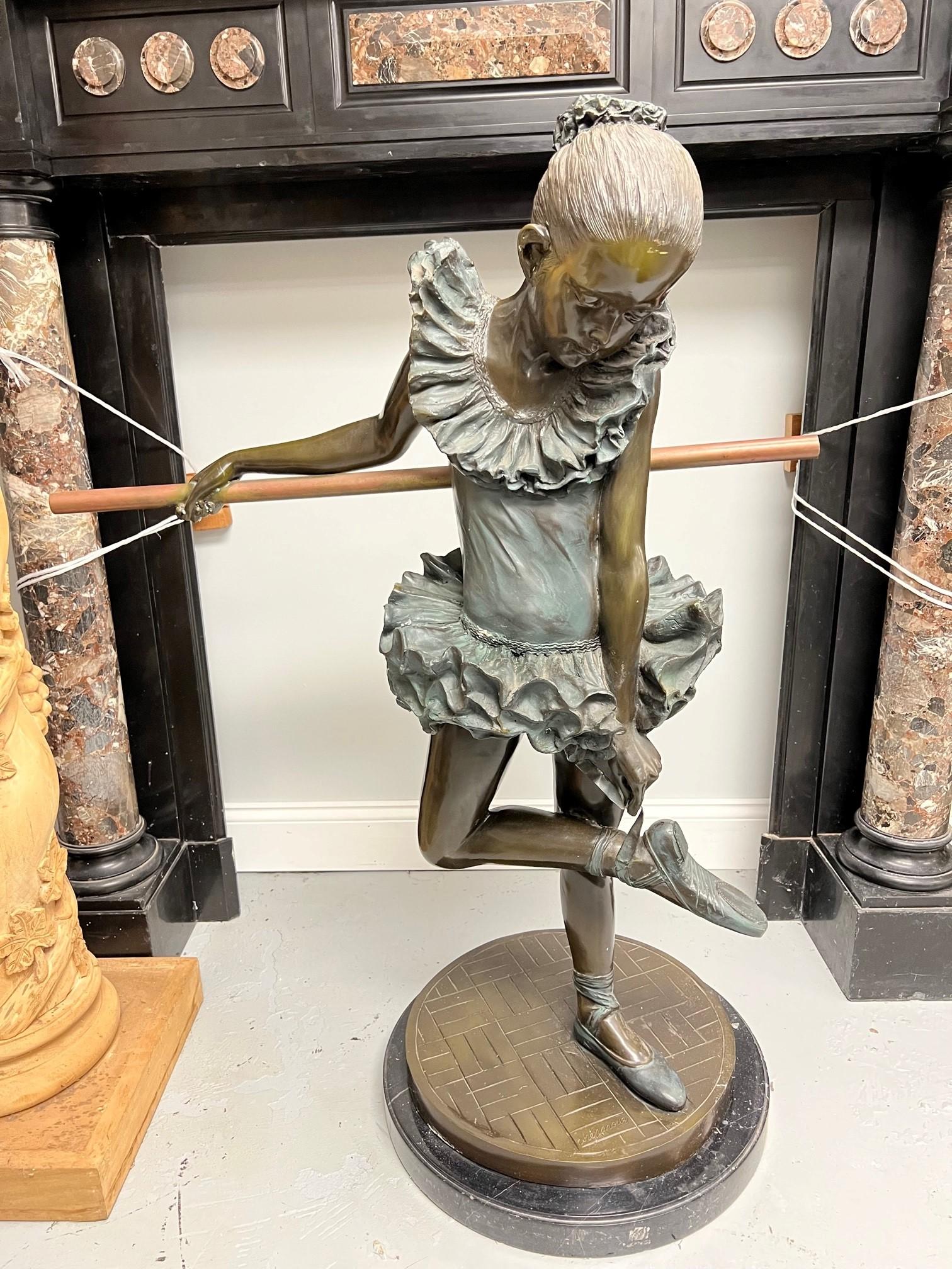Late 20th century bronze ballerina statue of a young girl on a marble base. The ballerina, a young girl is holding onto the barre a railing used for her pre-dance exercises adjusting her ballet shoe. Its a nice piece that can be used both indoor or