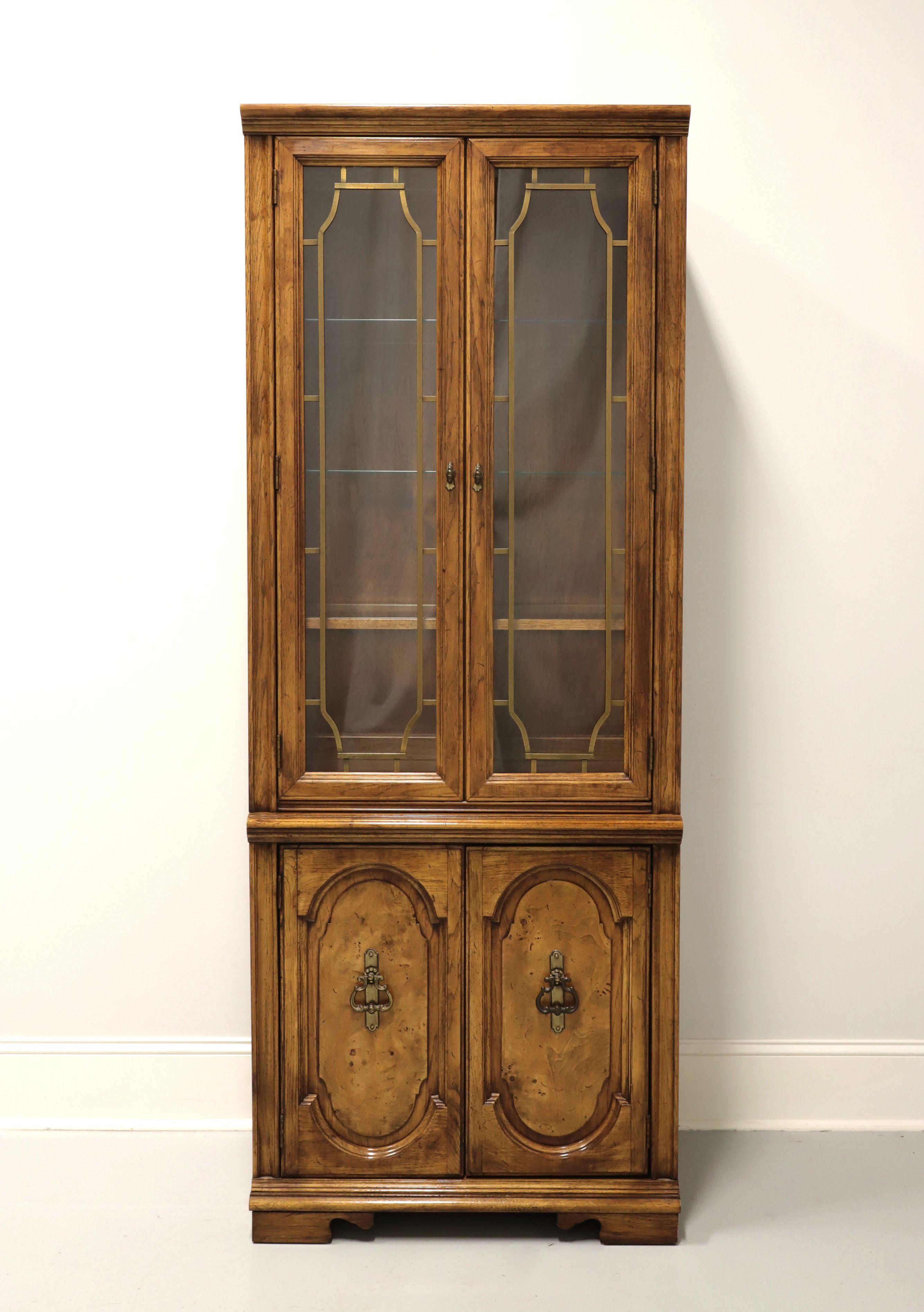 A Mediterranean style curio / display cabinet, unbranded, similar quality to Bassett or Henredon. Burl pecan with brass hardware. Upper cabinet with dual glass doors with brass fretwork, lighted interior, lower wood encased fixed plate grooved glass