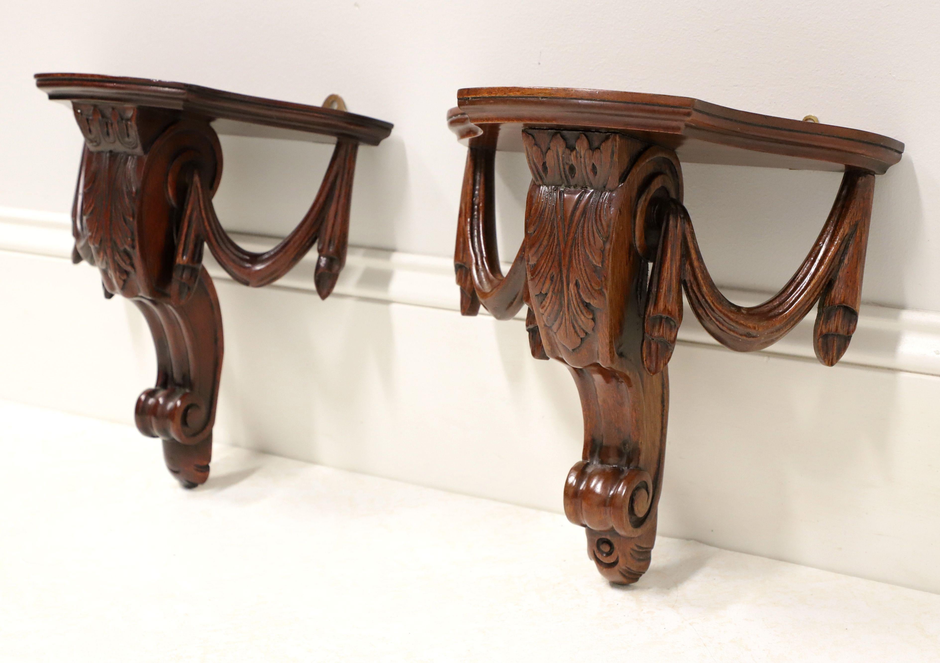 A pair of Chippendale style wall bracket shelves, unbranded. Solid mahogany with flat display surface, center support bracket adorned with carved acanthus leaf, and decorative drapery swags to side brackets. Dual brass hangers on back for wall