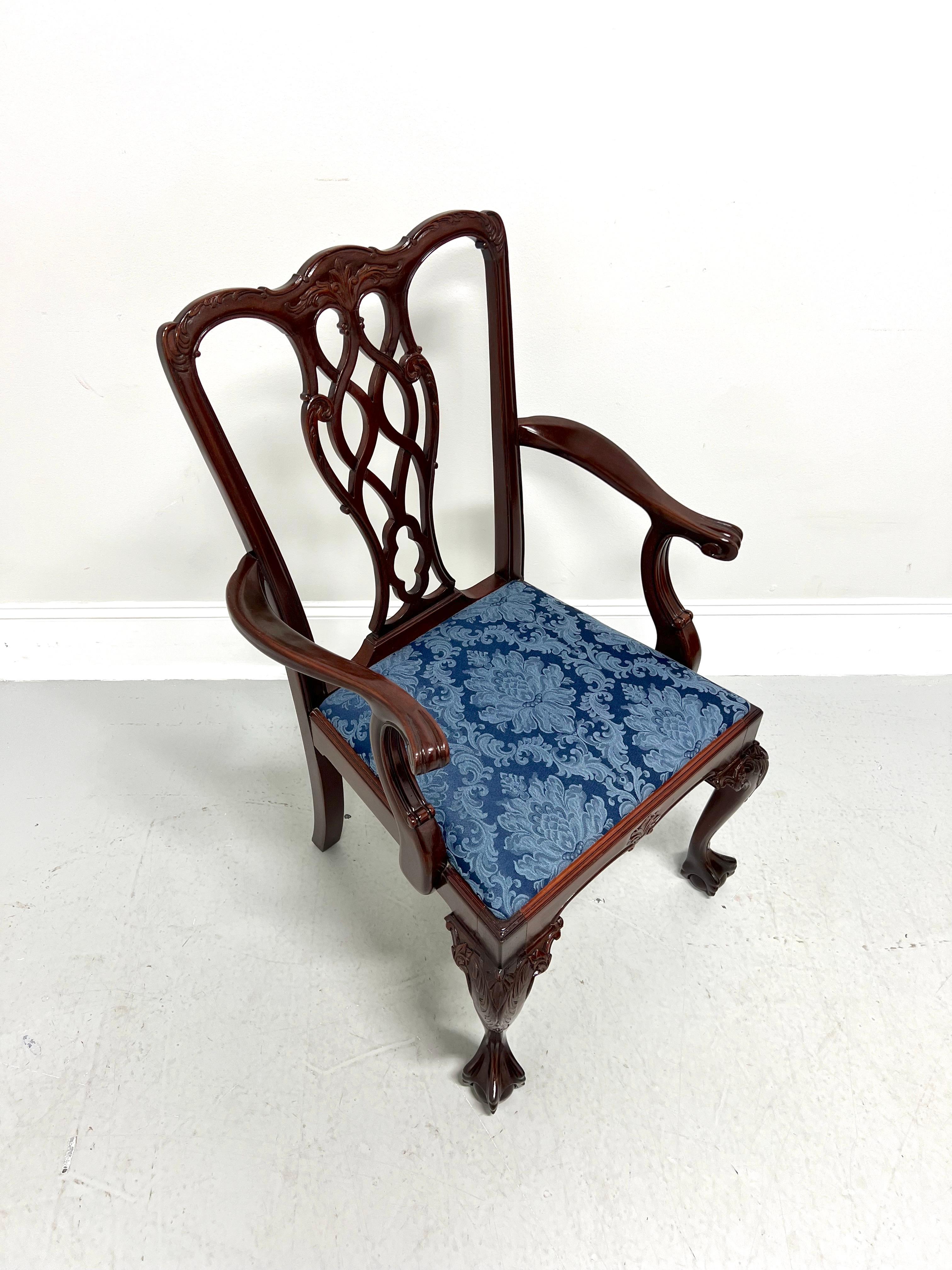 A Chippendale style armchair, unbranded. Solid mahogany with decoratively carved crest rail & backrest, curved carved arms with paw-like hand rests, fluted details to stiles, carved knees, cabriole front legs, and ball in claw feet. Seat is