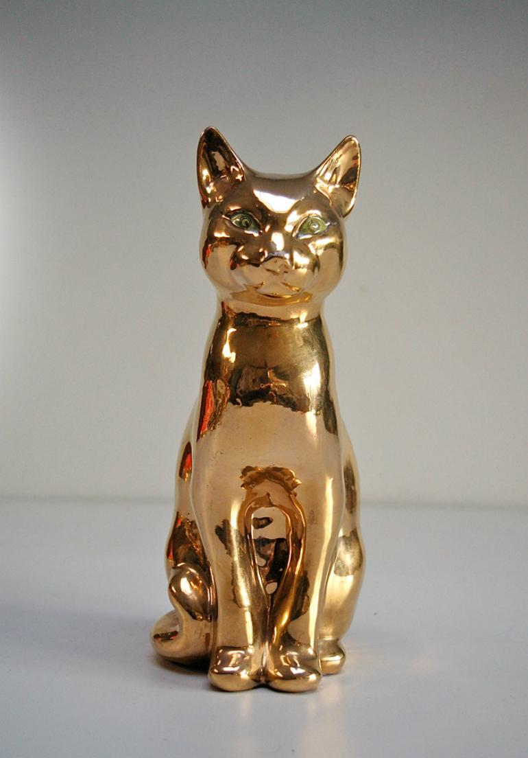 Ceramic cat with gold colored glaze finish and green eyes. The piece is signed at the bottom, but we were unable to identify the maker. Some signs of wear to the glaze, but overall in good vintage condition. 