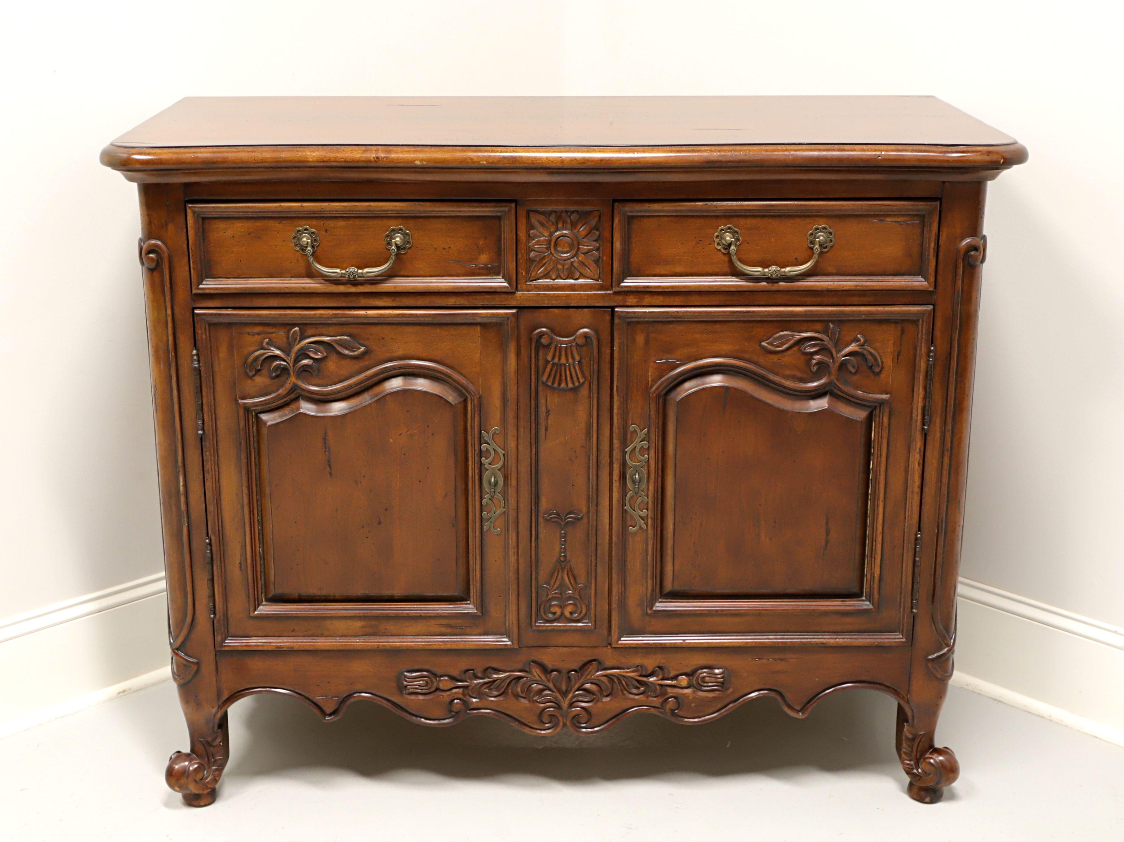 A French Country style server, unbranded, similar quality to Drexel Heritage or Thomasville. Solid cherry with brass hardware, decorative carvings, carved apron and scroll feet. Features two drawers of dovetail construction over a lower two door