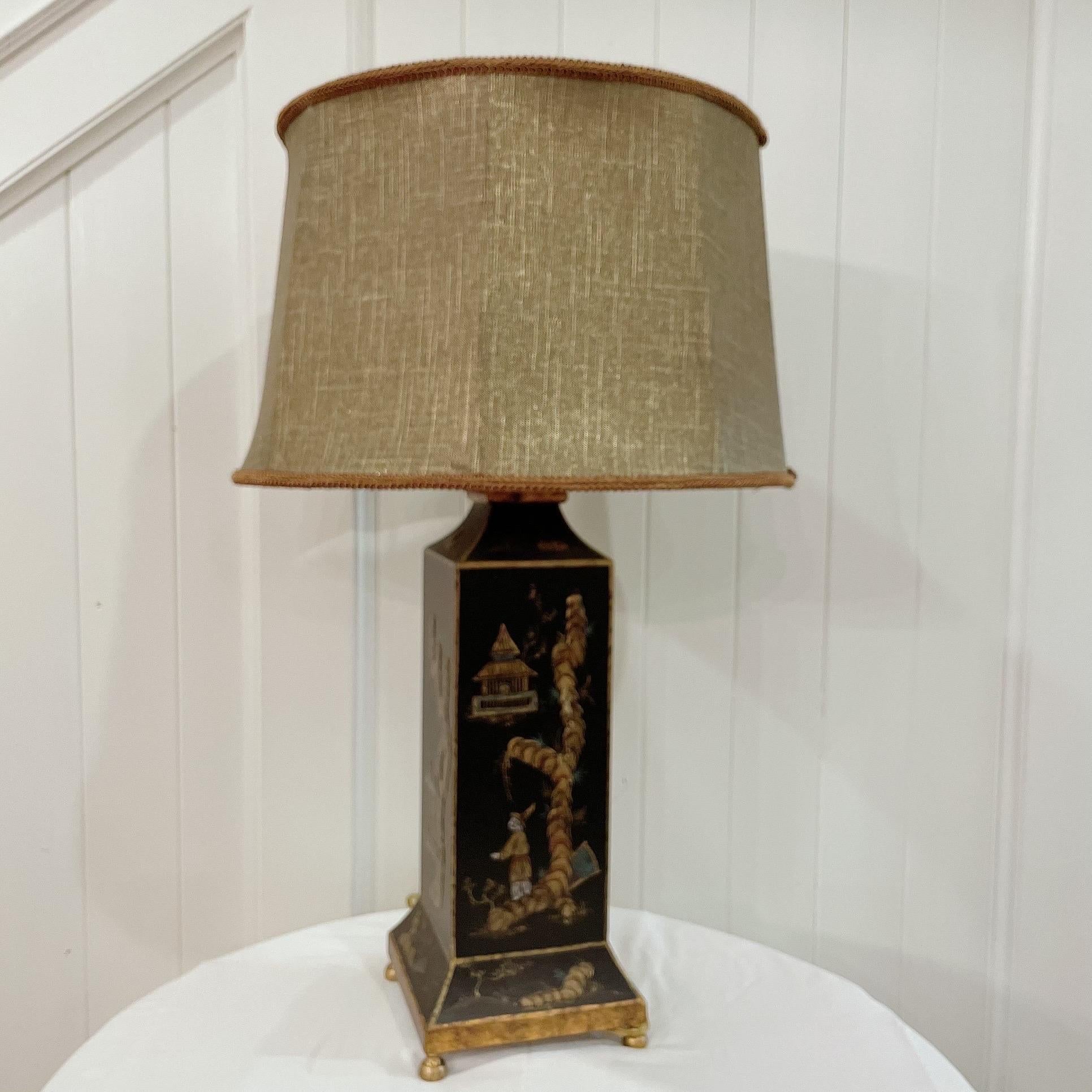 Vintage chinoiserie tole black lacquered lamp with a hand-decorated gilt design featuring pagodas, men, and flowers. A different scene on each side.