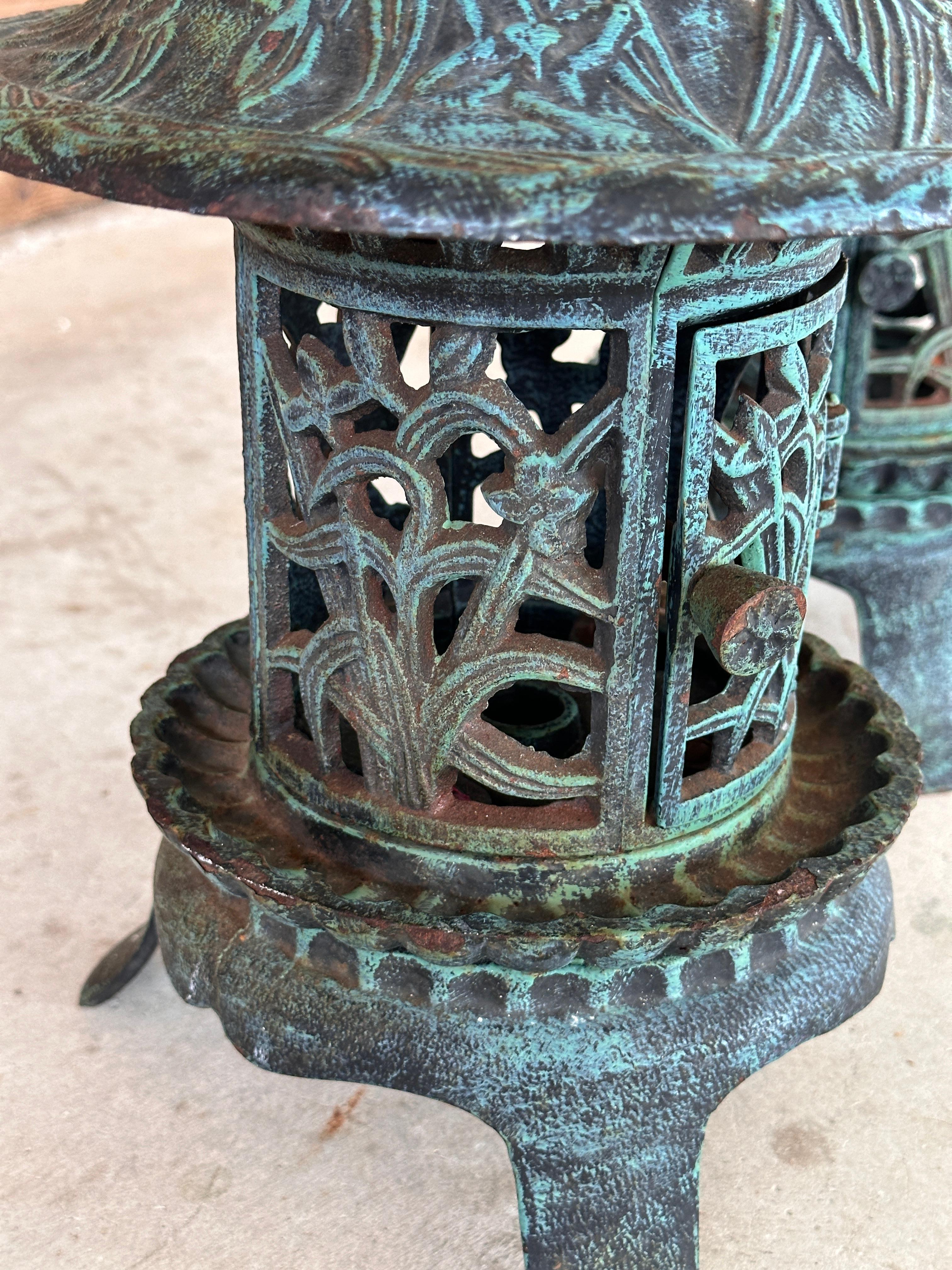 Pair of Late 20th Century cast iron pagoda lanterns with a stunning verdigris patina. These intricate lanterns feature detailed cut-out designs of floral and nature-inspired motifs, perfect for evoking an Asian garden aesthetic.
The doors open to