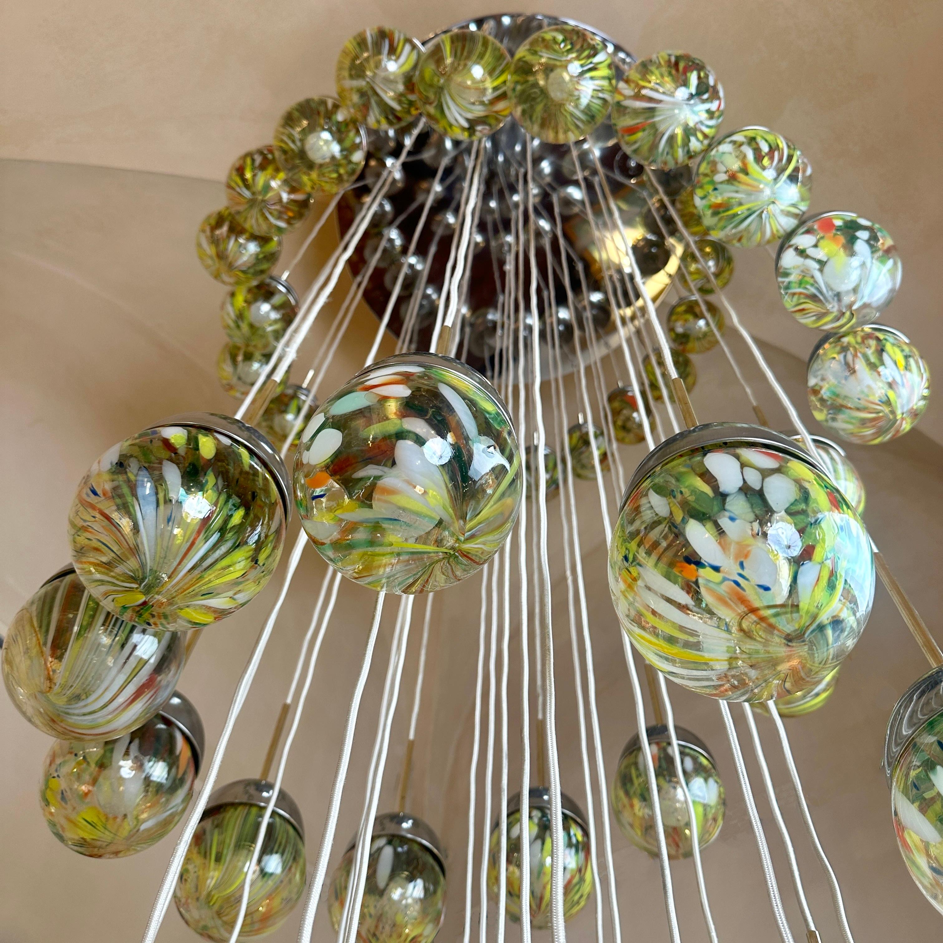 Impressive Murano Art Glass Cascade Chandelier with a true waterfall of light with 55 E14 LED Light Bulbs (warm light is recommended). 
The transparent Murano glass boules are all multicolored striated and stained making each piece different from