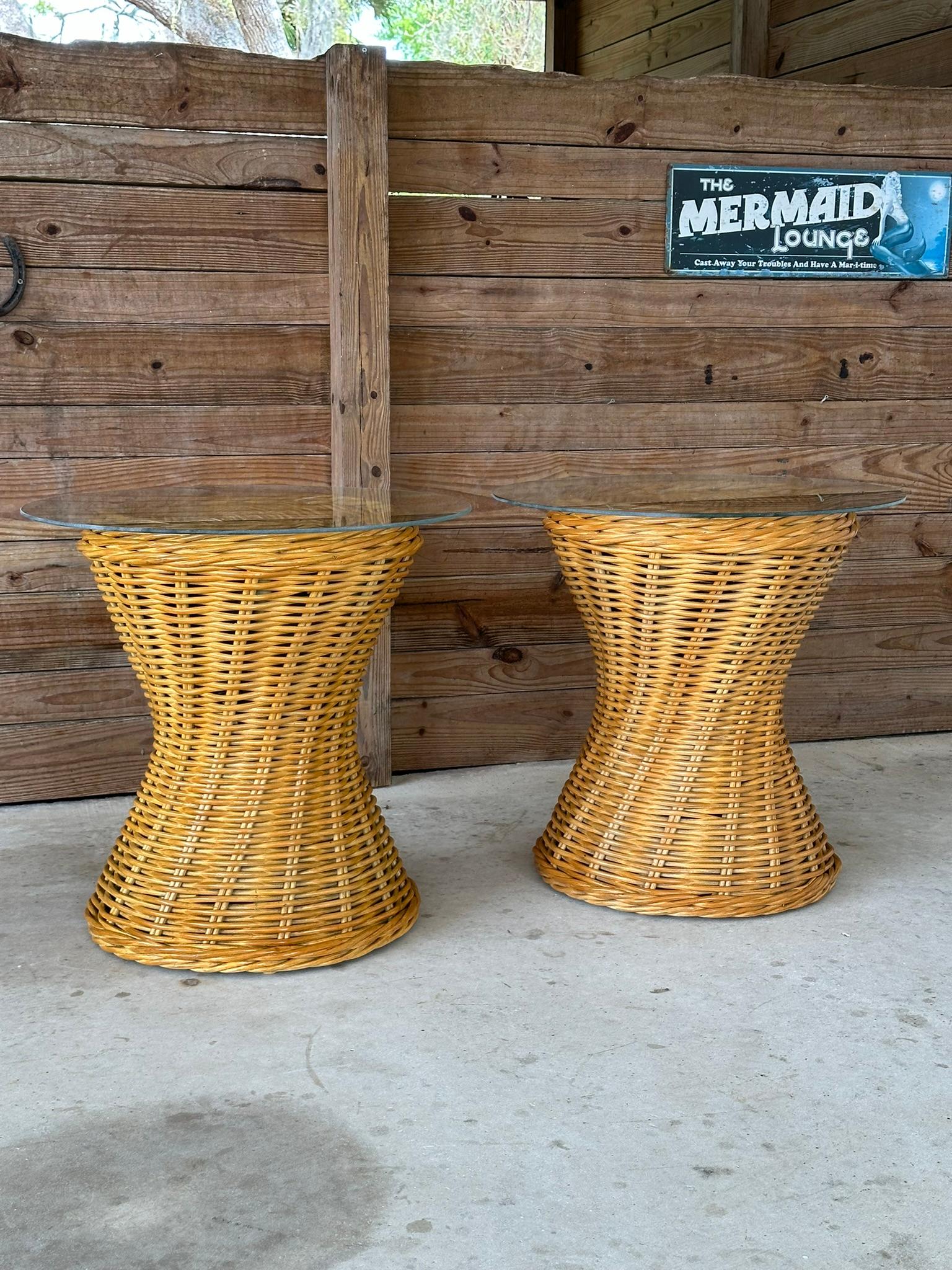 Presenting a stunning pair of vintage rattan braid hourglass-shaped side tables, now featuring brand-new round glass tops. Expertly refinished and stained, these tables exude a refined coastal charm, perfect for enhancing any interior space.

Please