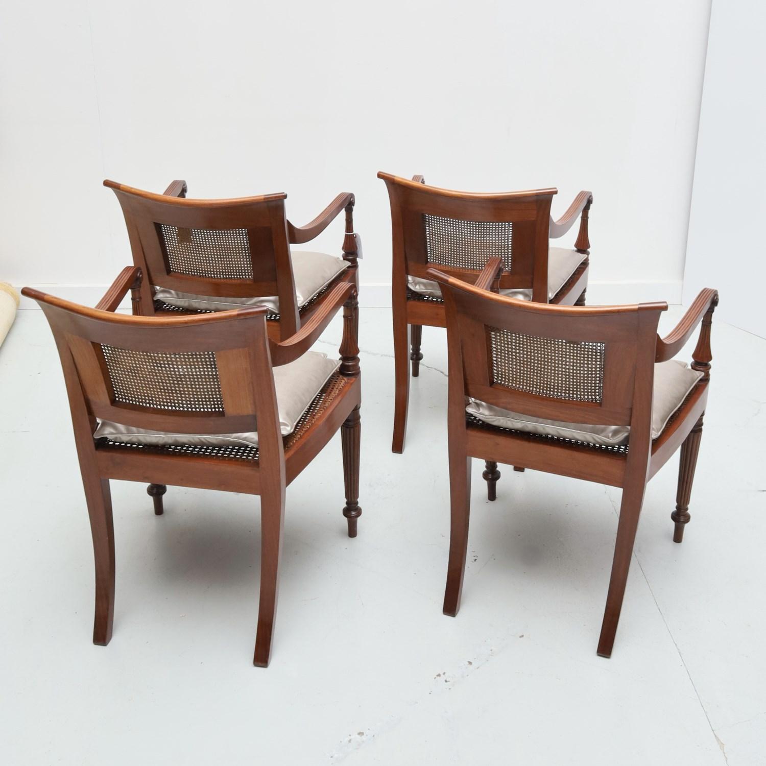 Late 20th, stylish and handsome mahogany arm chairs with scrolled backrest and arms, caned seat and back, on reeded legs ending in arrow feet, with metallic silver tone removable seat cushion, no visible maker's mark.

Dimensions:
31.5