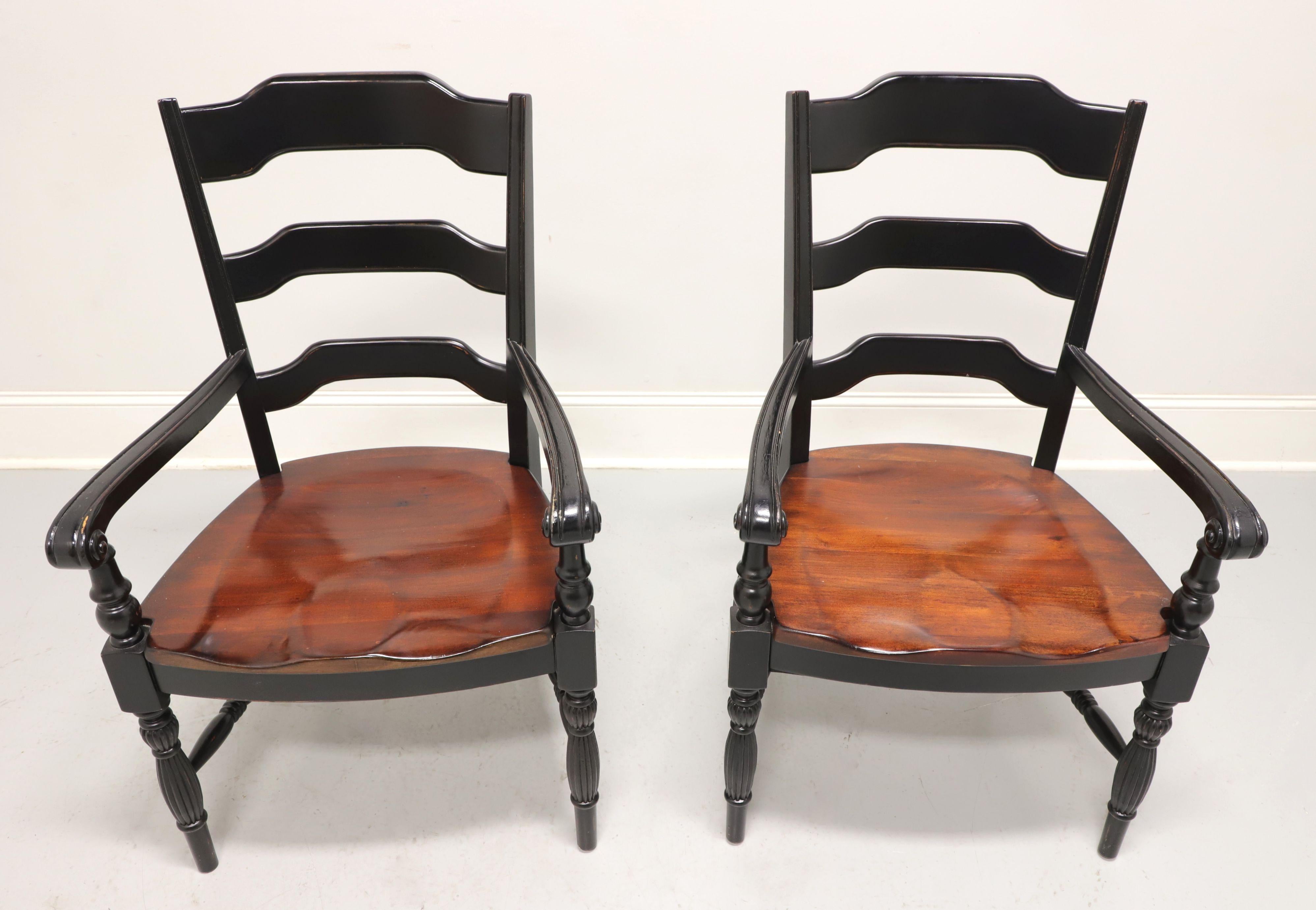 A pair of Cottage / Farmhouse style dining armchairs, unbranded. Hardwood with a distressed black painted finish, carved ladder backs, curved arms with turned supports, natural cherry saddle seats, turned & fluted legs and turned stretchers. Made in