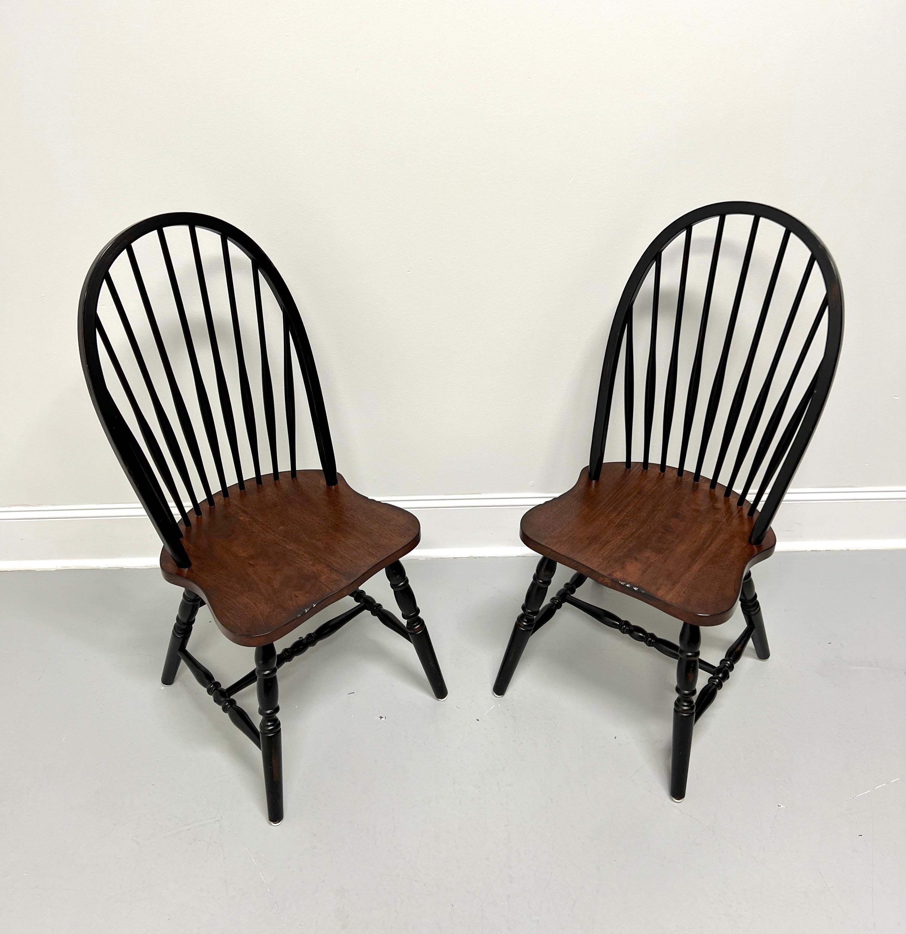 A pair of Windsor dining side chairs, unbranded. Nutwood with back, legs & stretchers painted black, bowback, tapered spindles, solid seat with a distressed stained finish, turned legs, and turned stretchers.  Made in the USA, in the late 20th